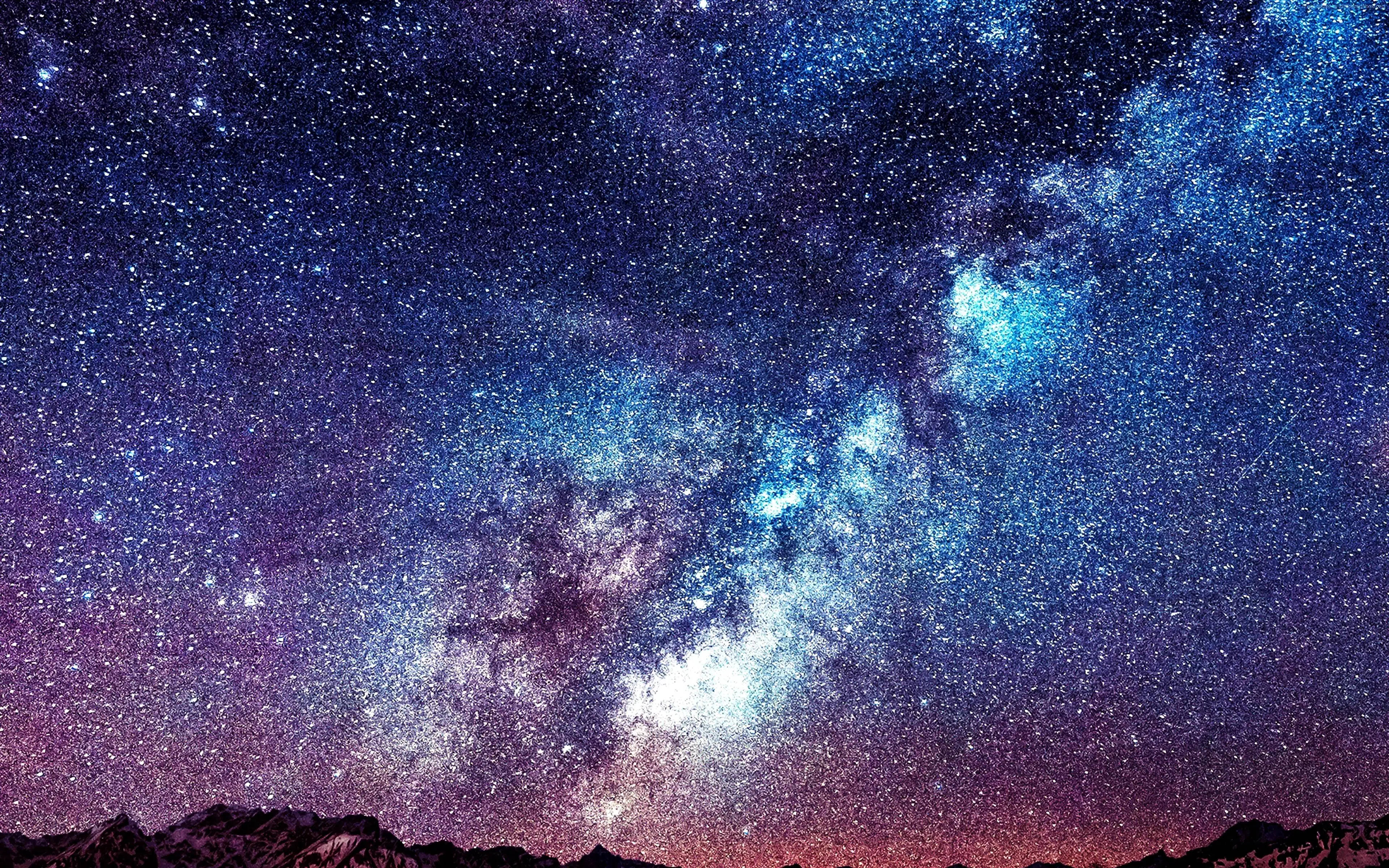 蘋果 桌布 壁紙 — 一個令人嘆為觀止的夜空，充滿了無數星星和發光的藍紫色星雲，拱起在鋸齒狀的山脈輪廓之上。