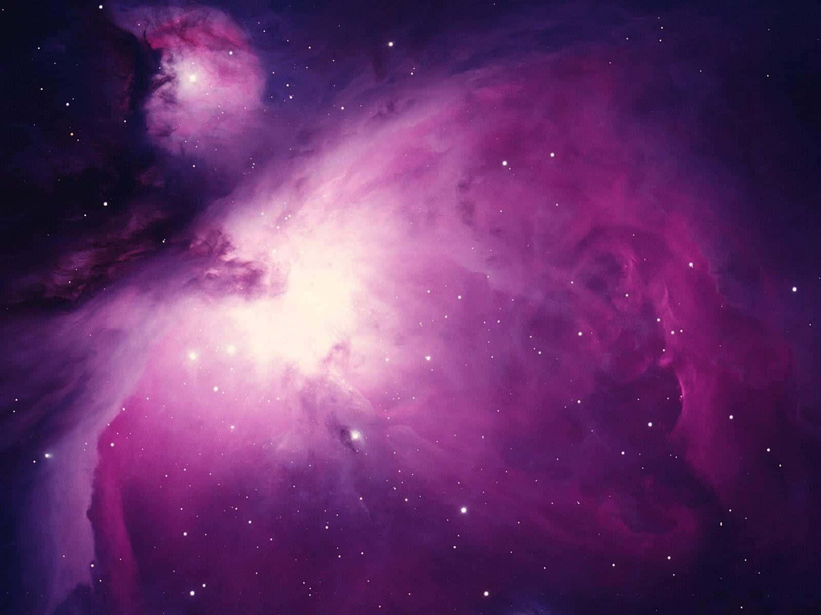 Purple Space 桌布 壁紙 — 一個令人嘆為觀止的宇宙星雲景觀，在佈滿星辰的黑暗虛空中散發著鮮豔的洋紅色和紫色色調。