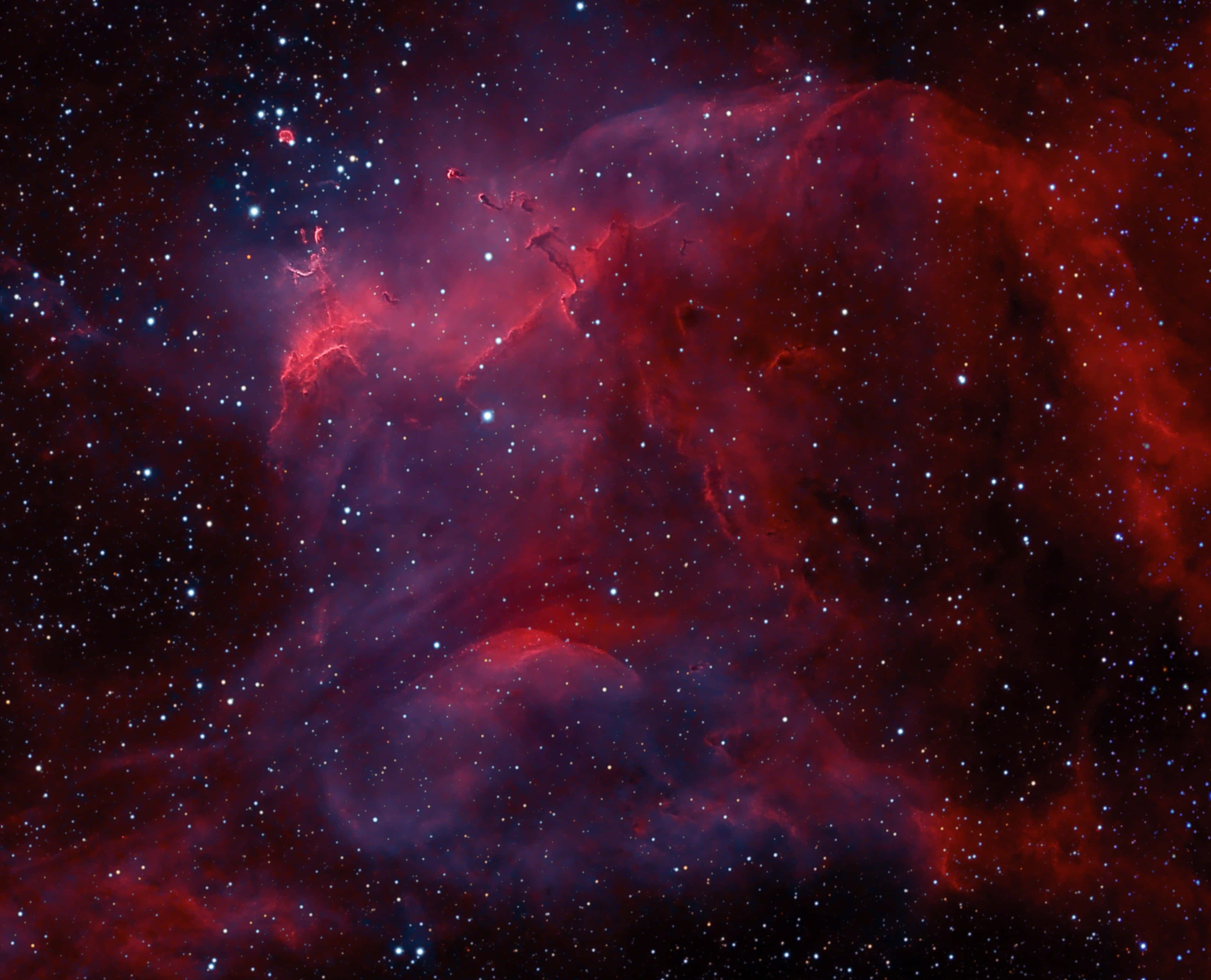 3d Star 桌布 壁紙 — 一個令人嘆為觀止的宇宙星雲景象，在佈滿星辰的黑色虛空中散發著深紅和紫色的光芒。