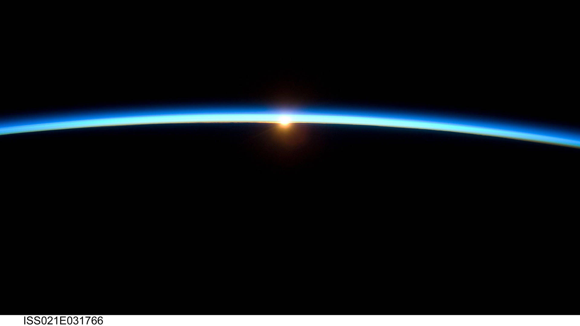 從太空看，地球彎曲的地平線在日出或日落時散發出藍色大氣光芒。 — 4K 地球 壁紙