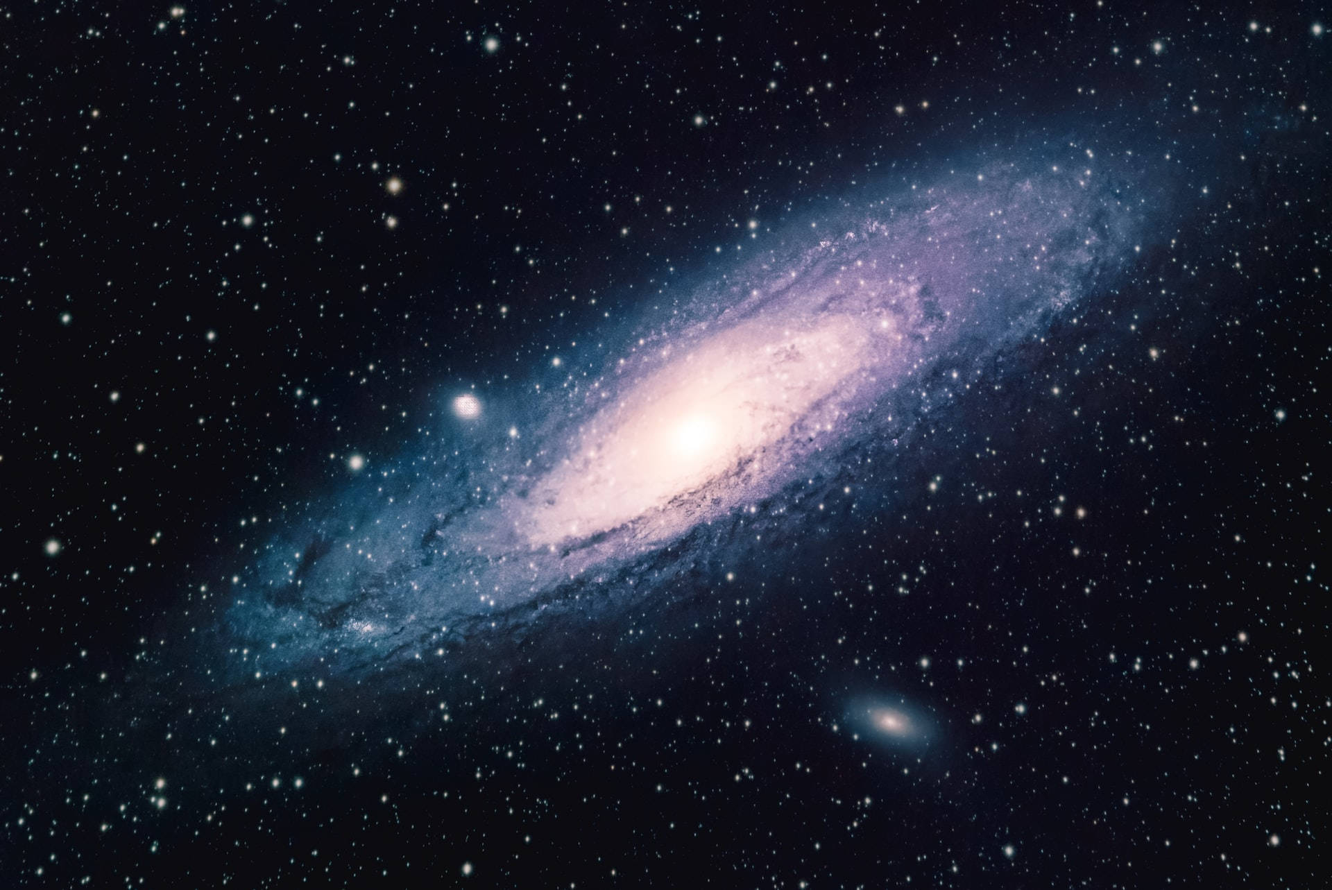 Stars 桌布 壁紙 — 一個令人嘆為觀止的螺旋星系，在佈滿星星的宇宙背景下散發出藍色和紫色的光芒。