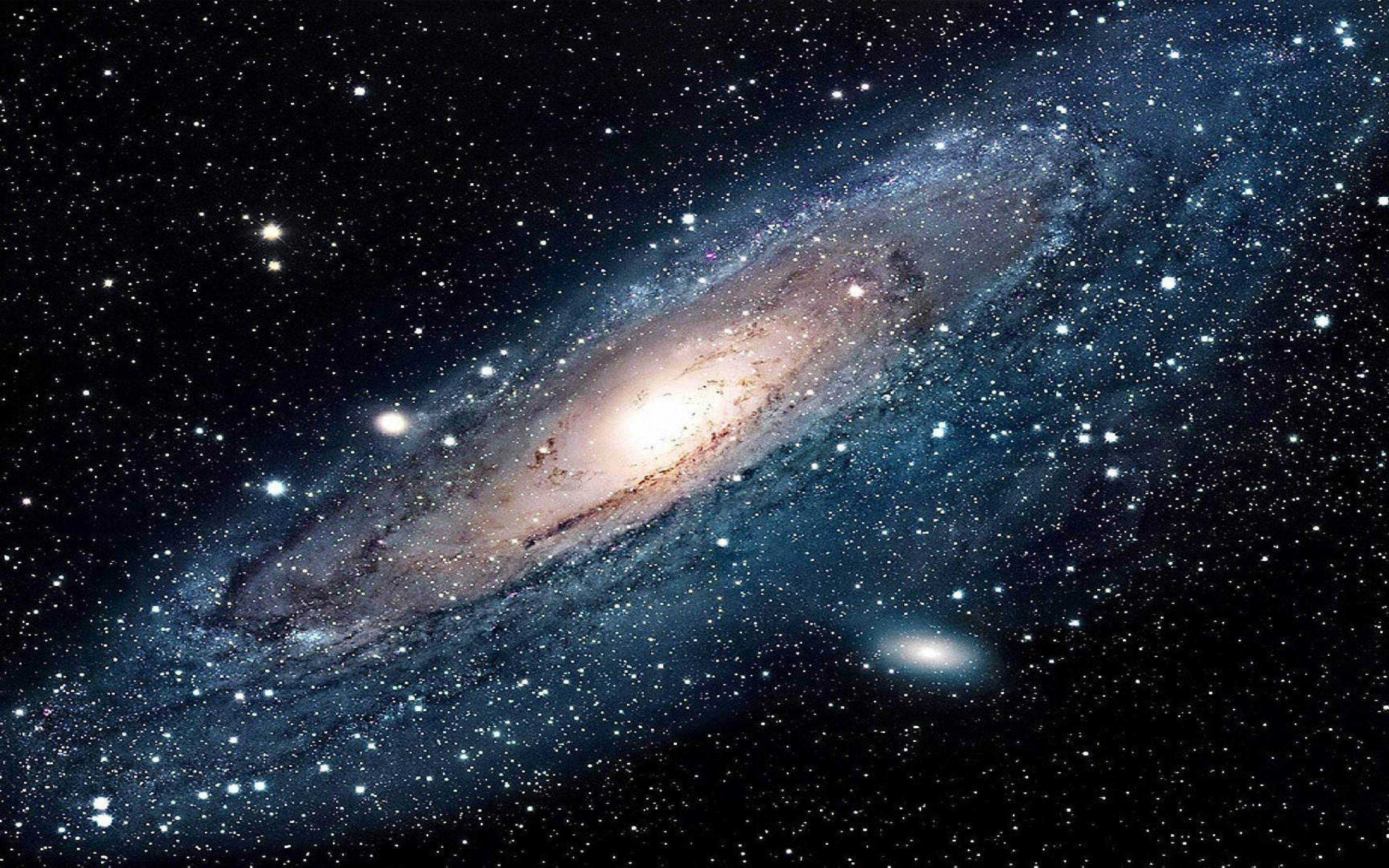 太空 桌布 壁紙 — 一個令人嘆為觀止的螺旋星系，在星空中散發著金色核心和藍色旋臂的光芒。