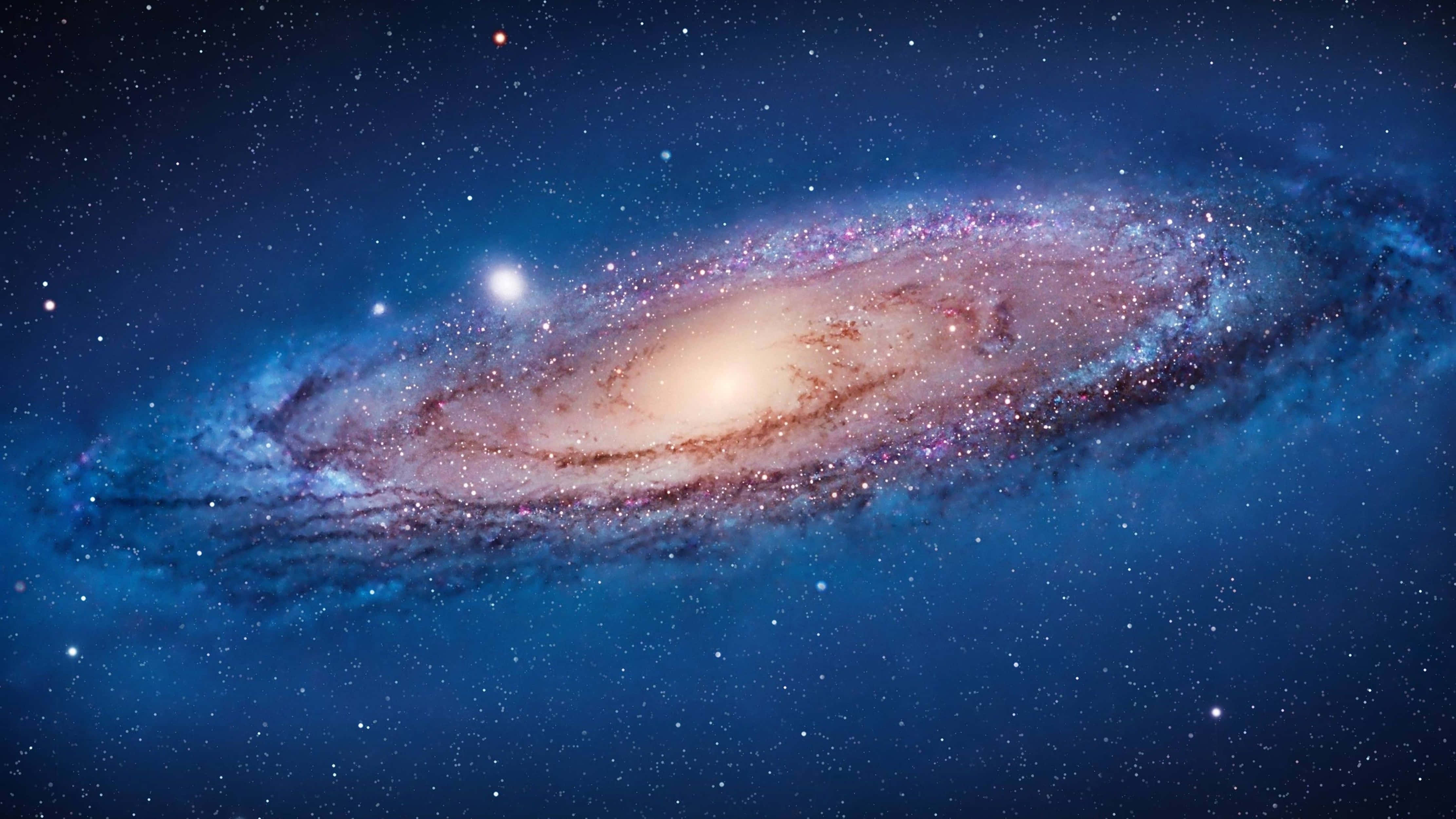 銀河 桌布 壁紙 — 一個令人嘆為觀止的螺旋星系，在深藍色星空中閃耀著粉紅色和金色的塵埃。