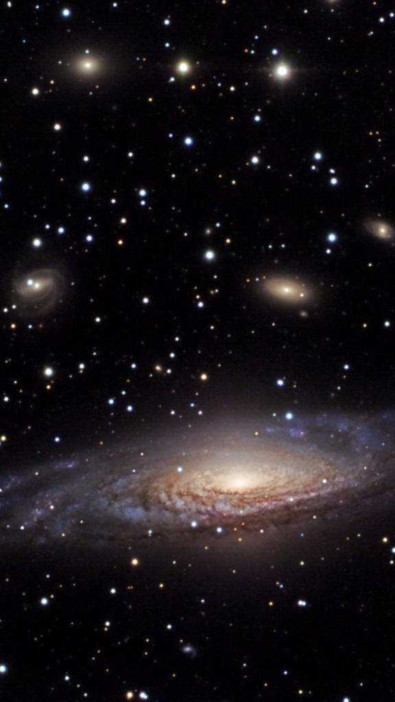 Galaxy Phone 桌布 壁紙 — 一個令人嘆為觀止的螺旋星系，在深邃的太空中散發著金色和藍色的光芒，被無數遙遠的恆星所環繞。