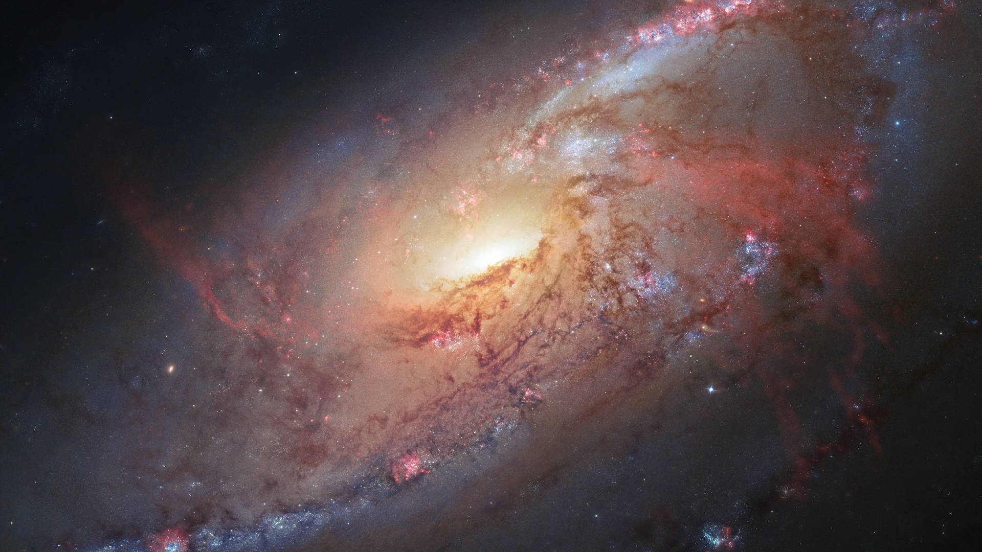 宇宙美學 桌布 壁紙 — 一個令人嘆為觀止的螺旋星系，在繁星點點的宇宙背景下，旋轉著發光的橙色和紅色星雲。