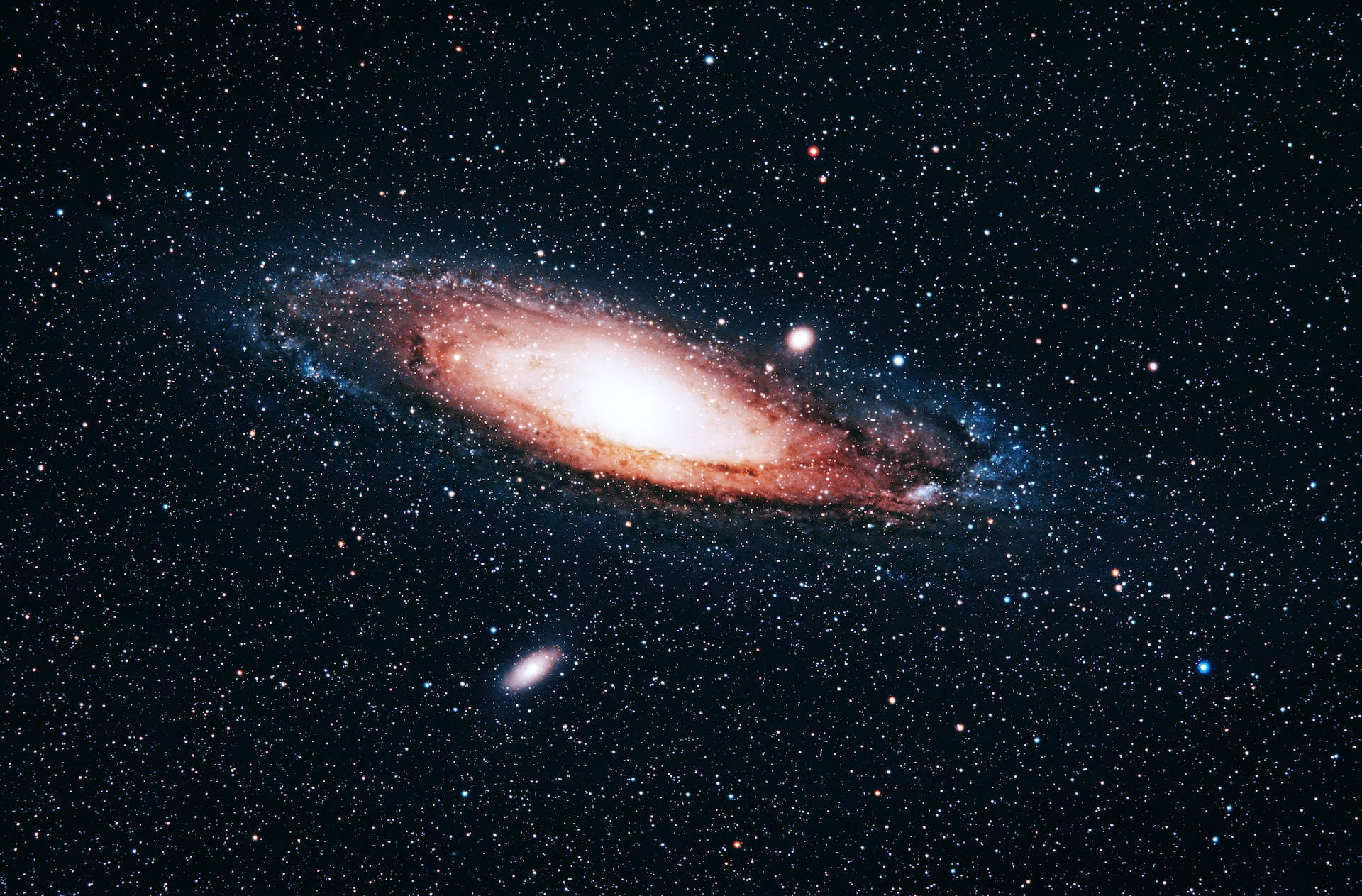 Stars 桌布 壁紙 — 一個令人嘆為觀止的螺旋星系，在繁星點點的宇宙背景下散發出橙色和藍色的光芒。