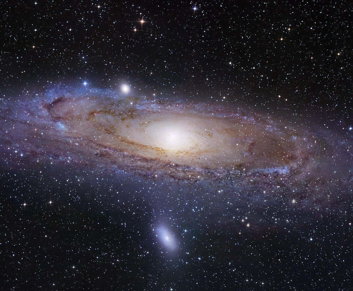 銀河 桌布 壁紙 — 一個令人嘆為觀止的螺旋星系，在繁星點點的宇宙背景下閃耀著金色和藍色的光芒。