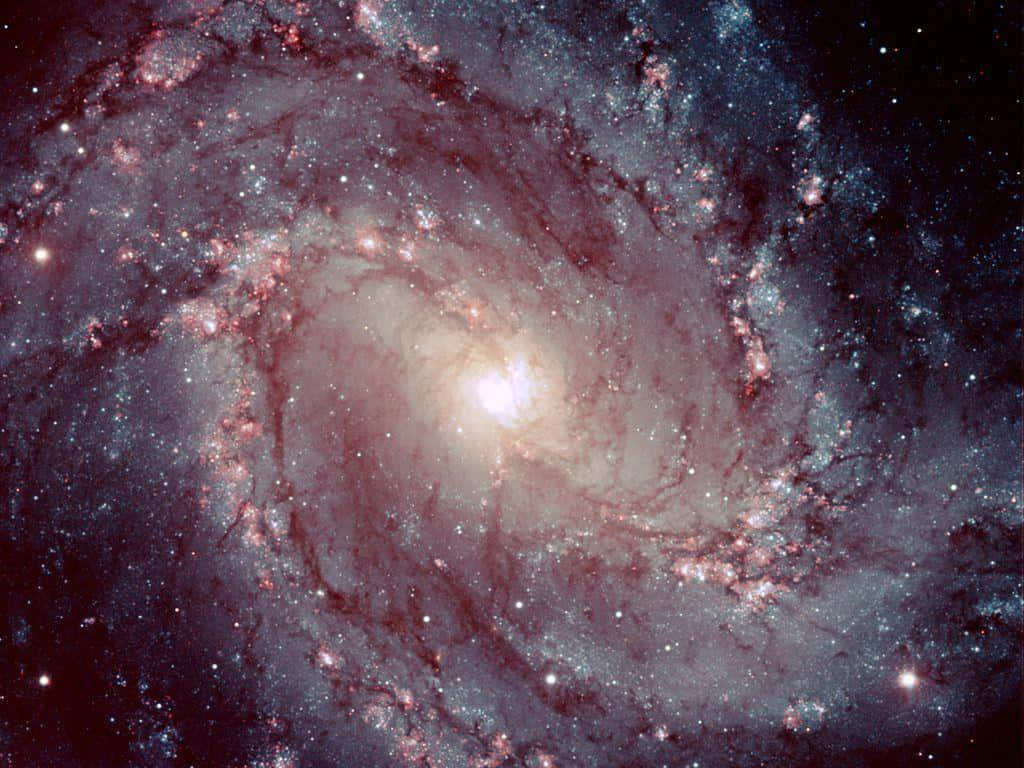 Spiral Galaxy 桌布 壁紙 — 一個令人嘆為觀止的螺旋星系，在繁星點點的宇宙背景下，旋轉著發光的粉紅色和藍色星雲。