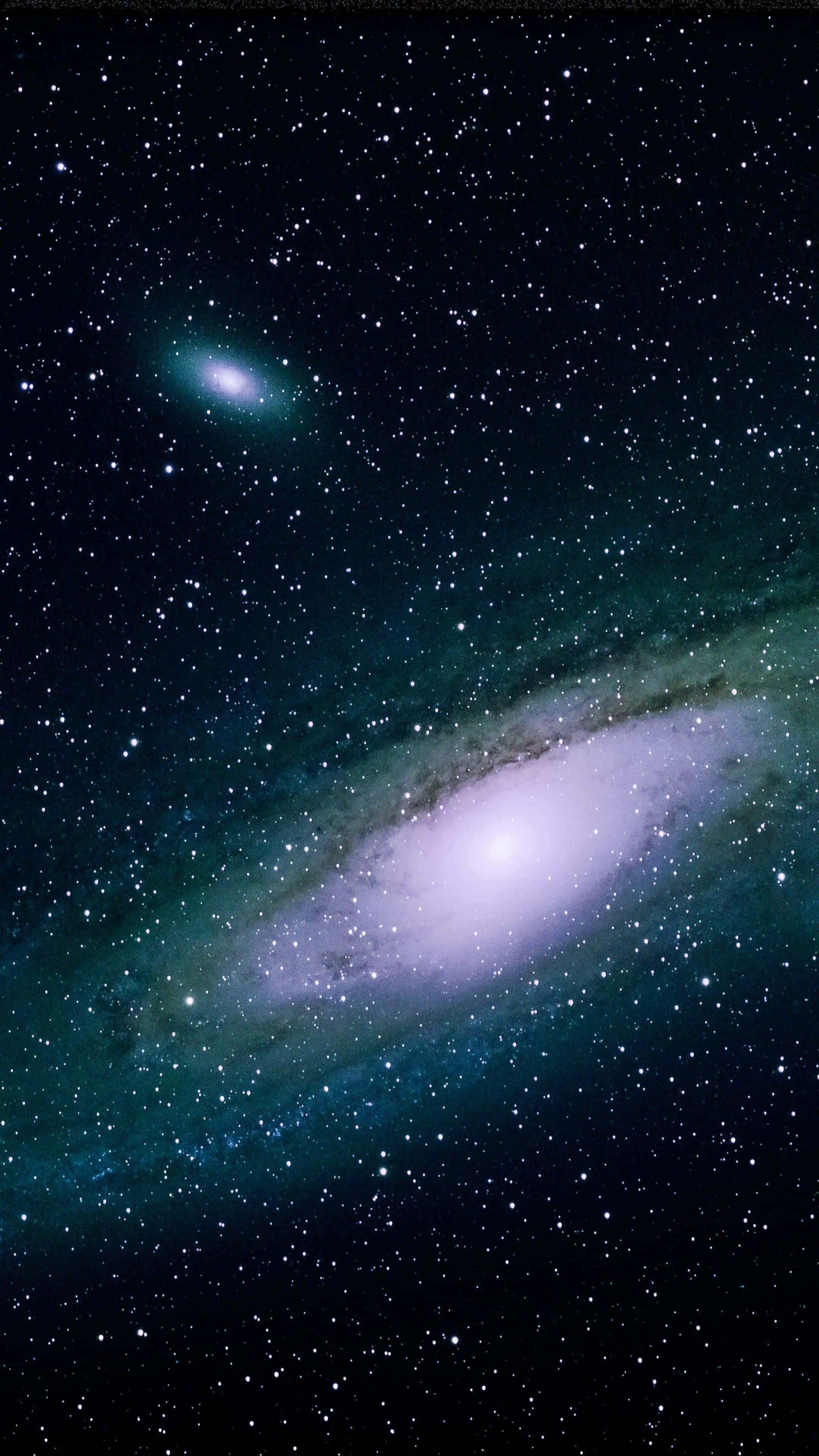 太空 桌布 壁紙 — 一個令人嘆為觀止的螺旋星系，在繁星點點的宇宙背景下散發著青綠色和白色的光芒。