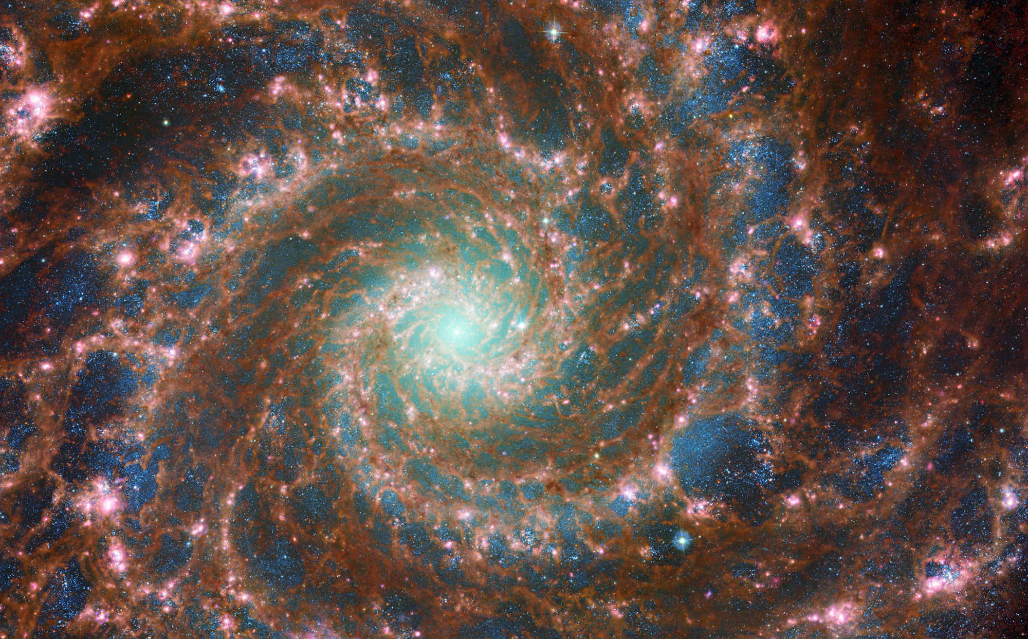 太空 桌布 壁紙 — 一個令人嘆為觀止的螺旋星系，在黑暗的宇宙背景下旋轉著發光的橙色旋臂和明亮的藍色星團。