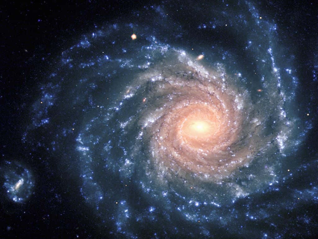 Elliptical Galaxy 桌布 壁紙 — 一個令人嘆為觀止的螺旋星系，擁有發光的橙色核心和充滿恆星的旋轉藍色旋臂，背景是黑暗的宇宙。