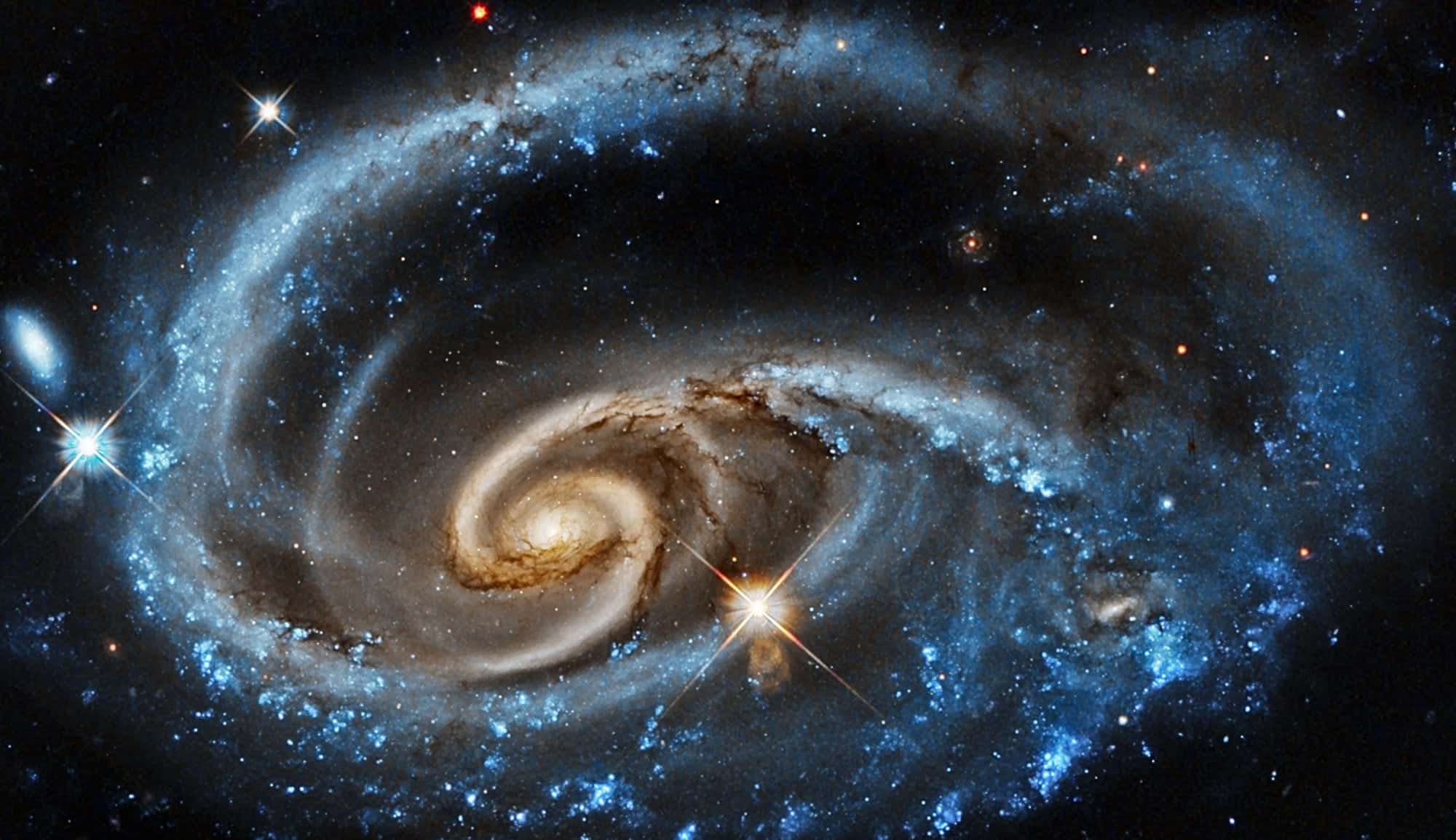 Nasa Galaxy 桌布 壁紙 — 一個令人嘆為觀止的螺旋星系，藍色星團和金色塵埃帶在繁星點點的宇宙虛空中旋轉。