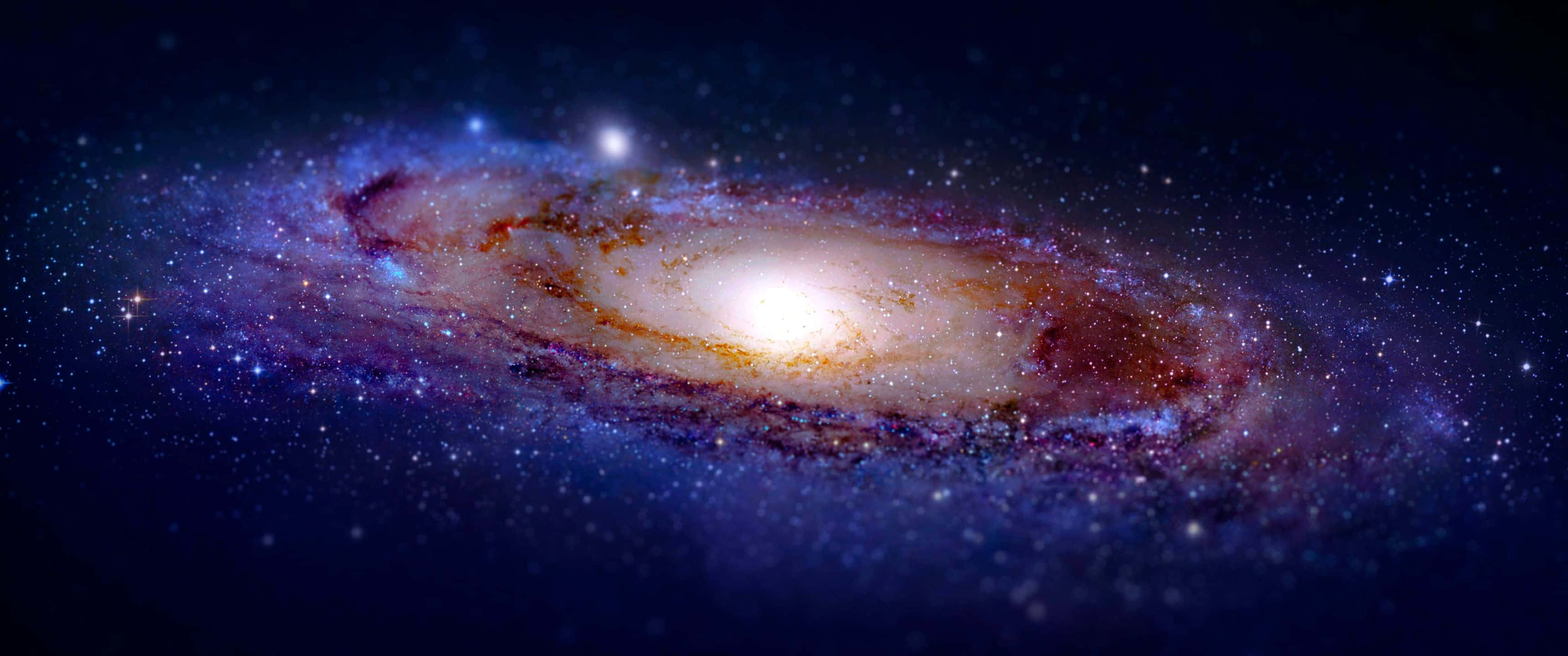 銀河 桌布 壁紙 — 一個令人嘆為觀止的螺旋星系，金色核心和藍色、紫色、橙色的旋臂在星場中閃耀。