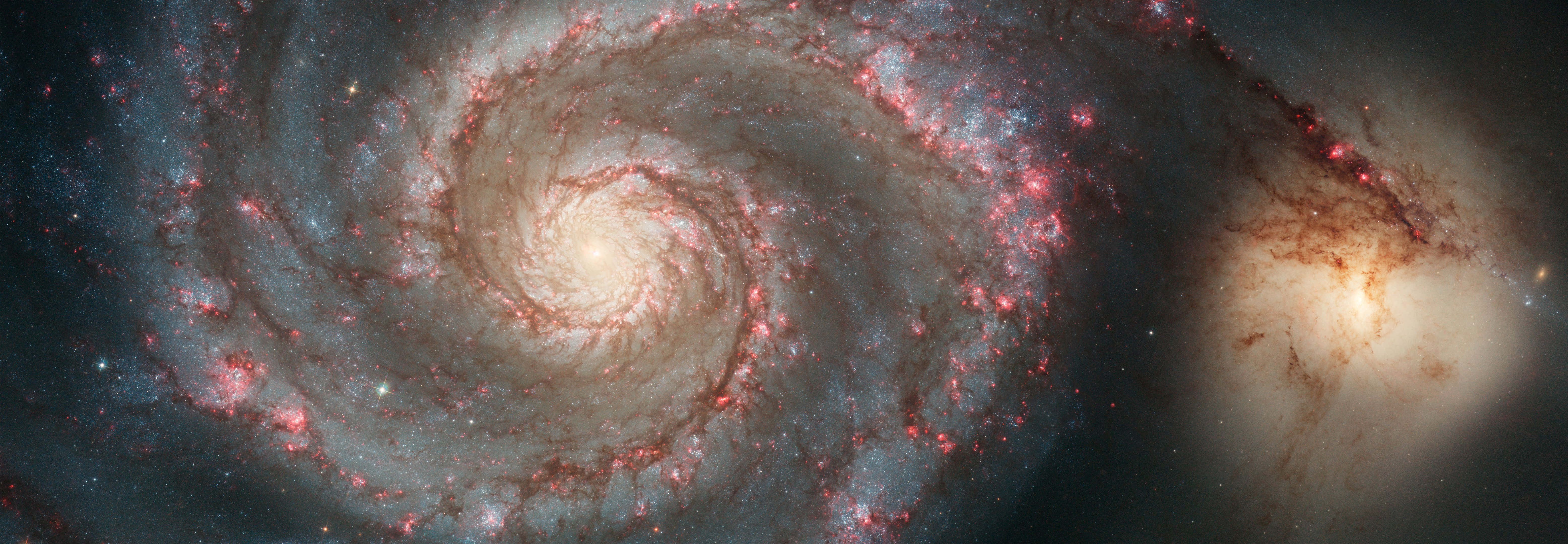 Whirlpool Galaxy 桌布 壁紙 — 一個令人嘆為觀止的螺旋星系在黑暗虛空中旋轉，閃爍著紅色恆星和宇宙塵埃。
