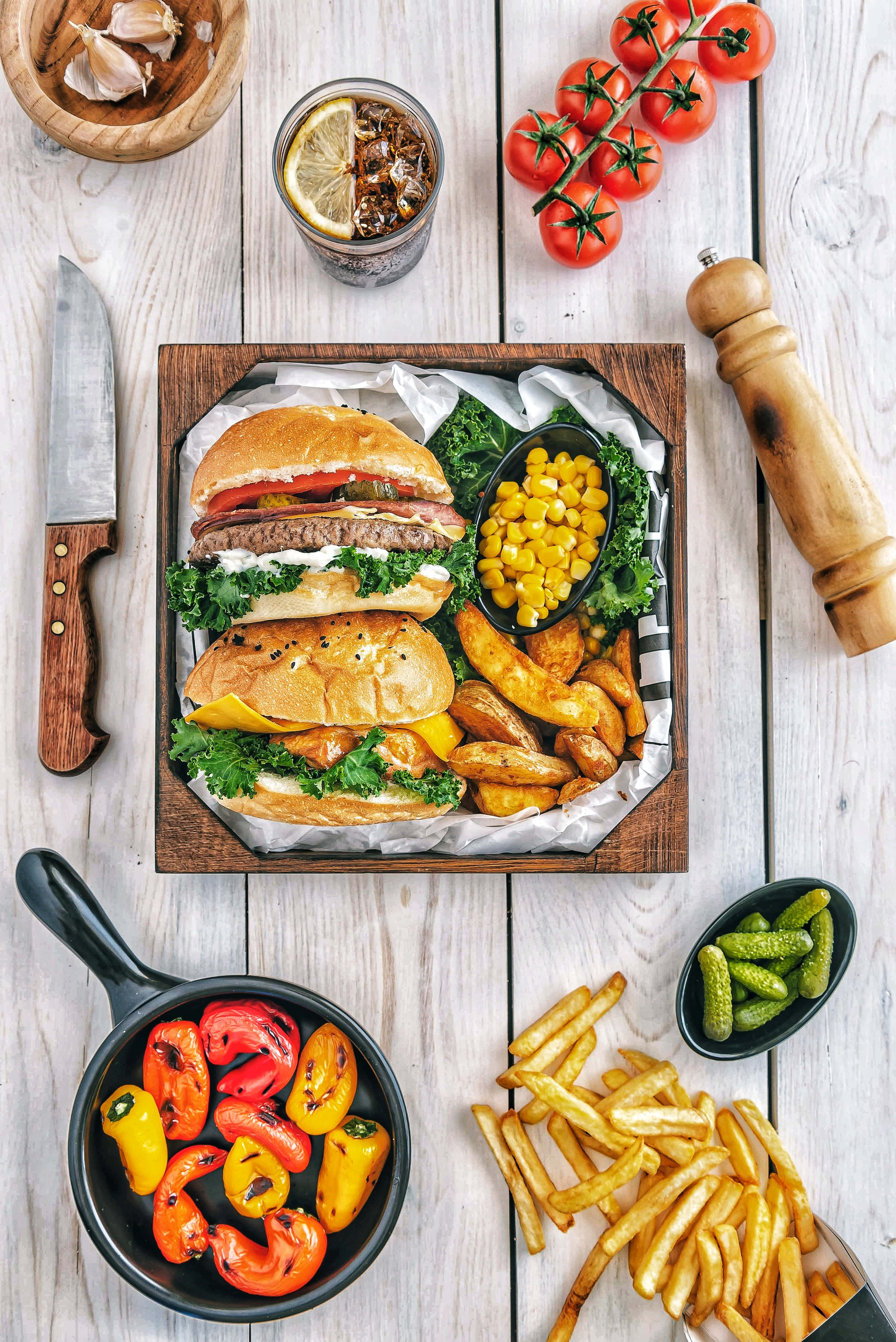 Food Table 桌布 壁紙 — 一個令人垂涎的漢堡，配上薯條和烤甜椒，擺放在白色木桌上的質樸木托盤上。