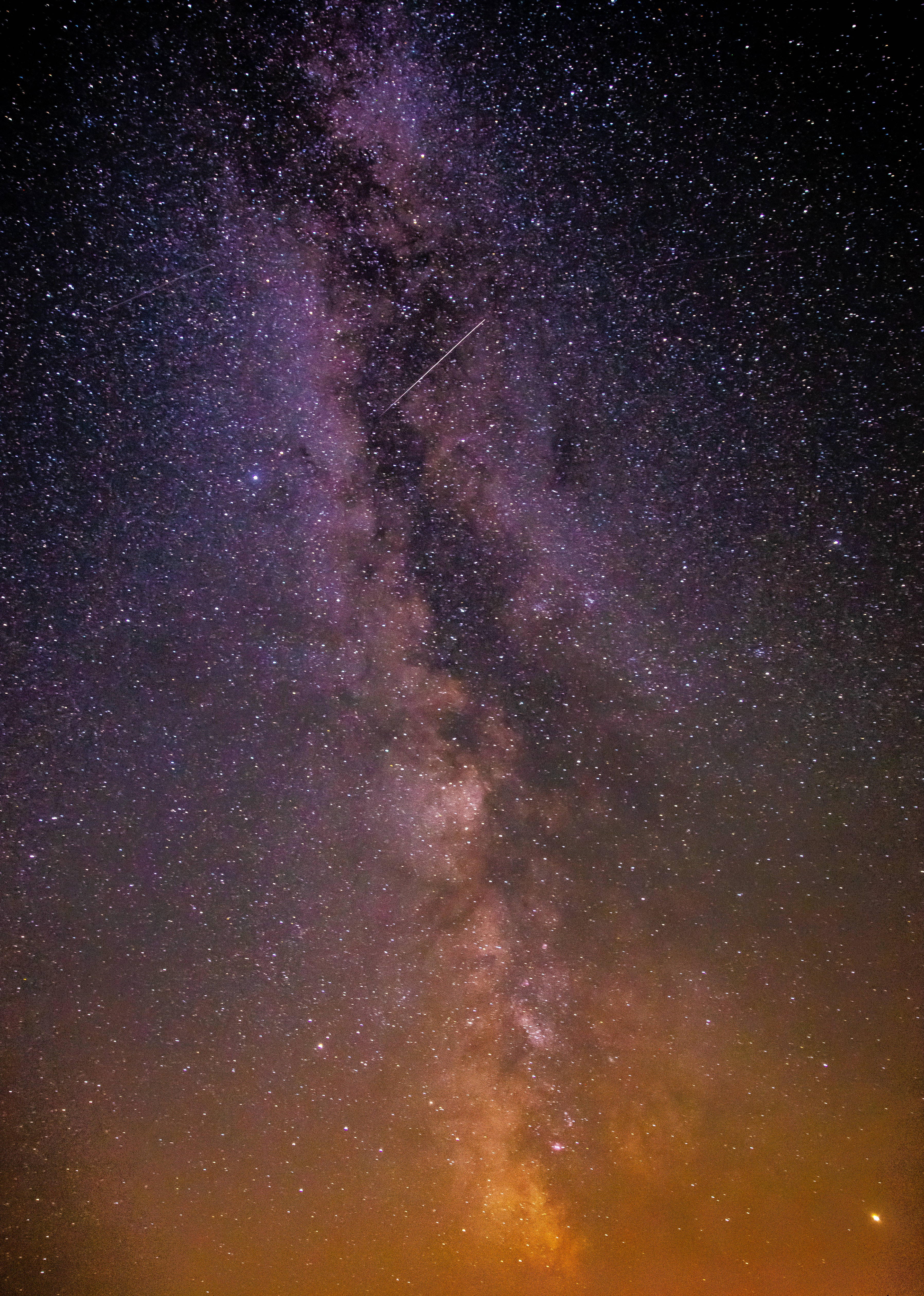 Stars 桌布 壁紙 — 一個令人屏息的夜空，佈滿星星和銀河，散發著紫色和橙色的光芒，並有一顆流星劃過。