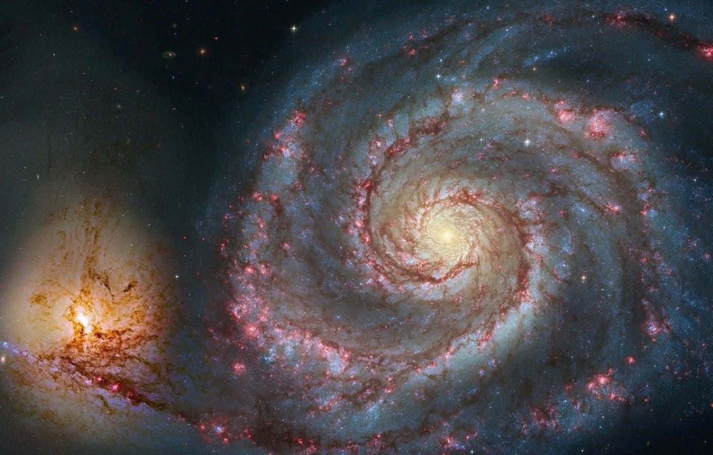 Whirlpool Galaxy 桌布 壁紙 — 一個令人屏息的螺旋星系，在繁星點點的宇宙背景下旋轉著發光的粉紅色和藍色星雲。