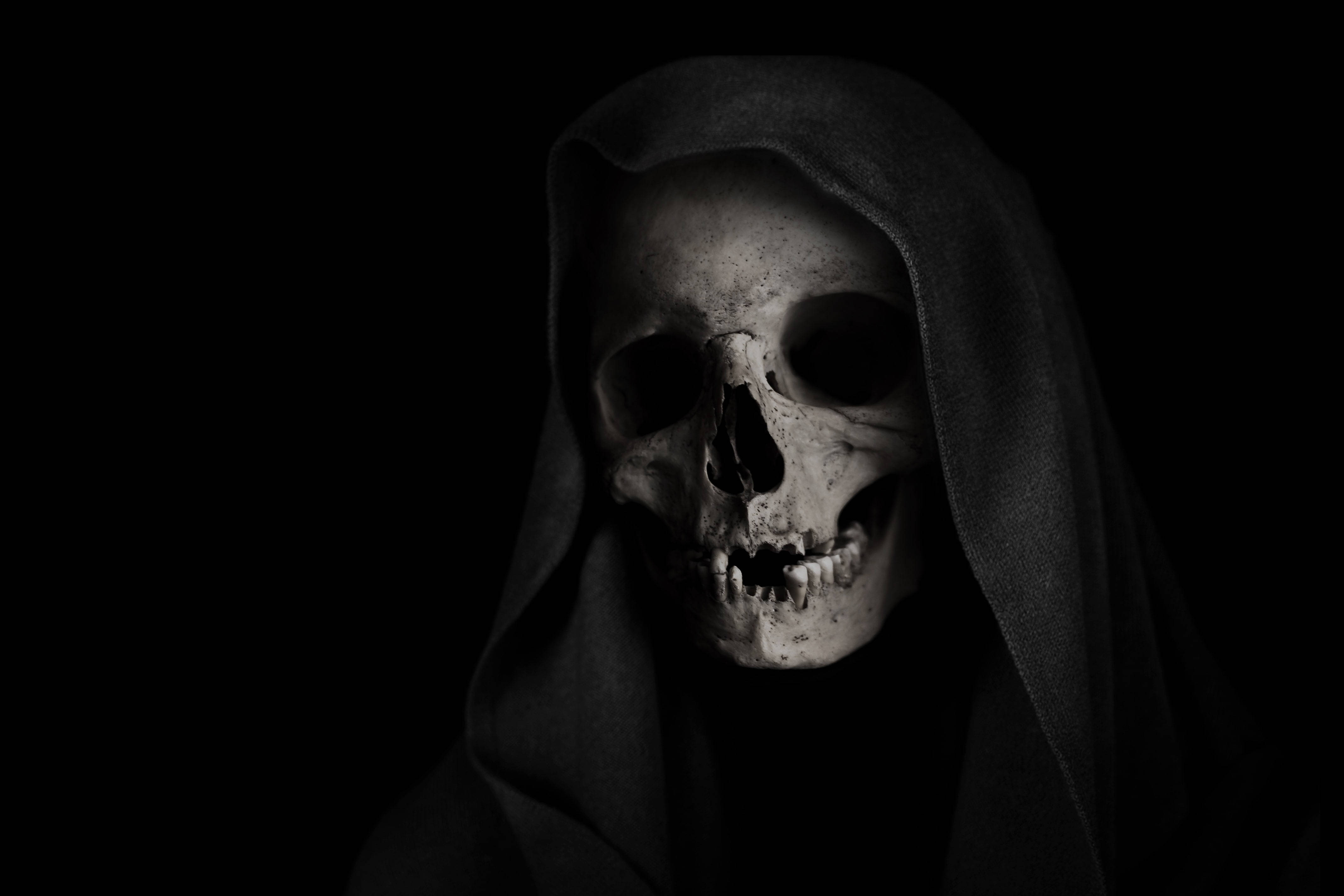 Most Scary 桌布 壁紙 — 一個令人毛骨悚然的人類頭骨，披著深色兜帽，襯托在純黑色背景上。