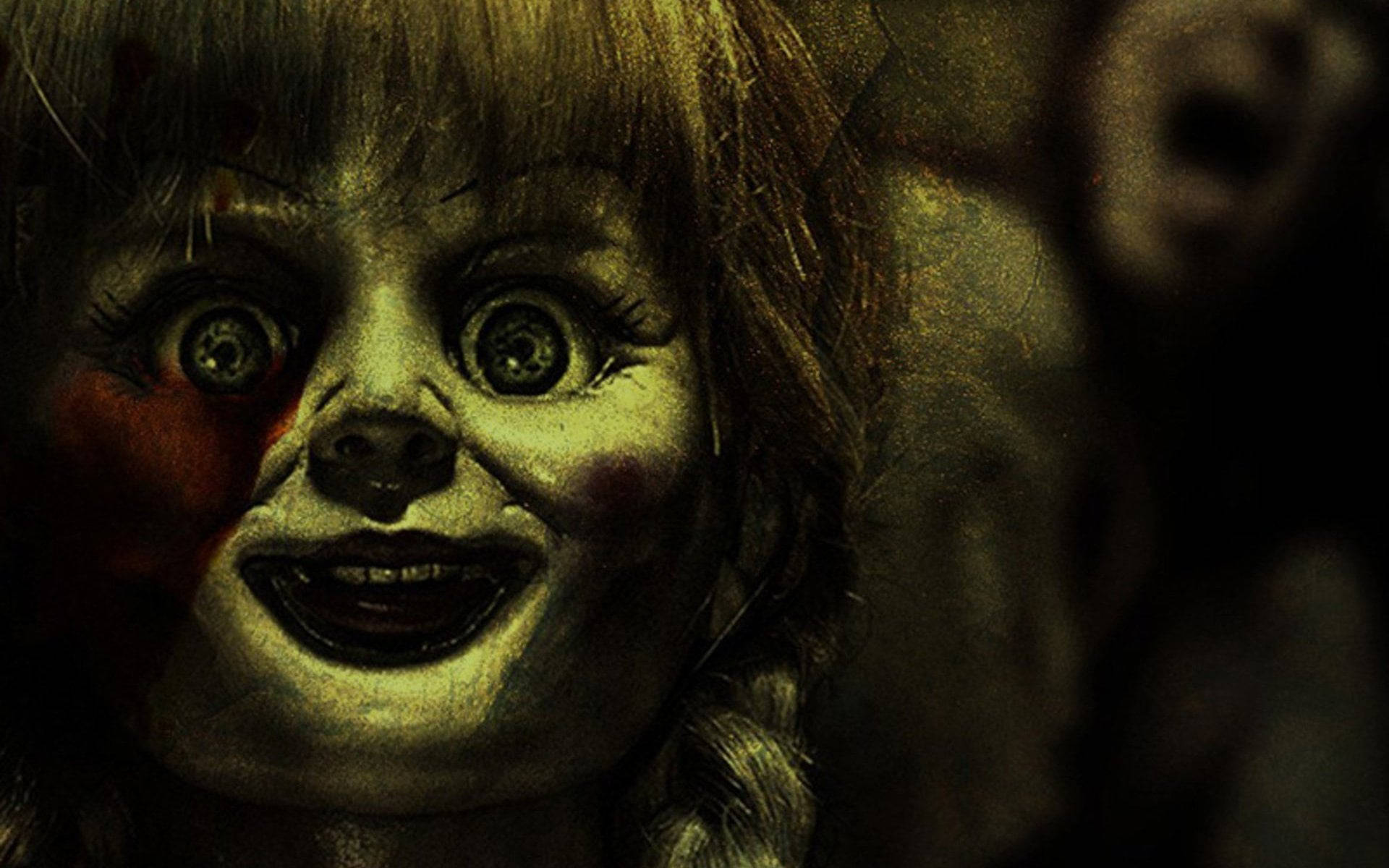Annabelle 桌布 壁紙 — 一個令人毛骨悚然的娃娃特寫，大眼睛和邪惡的笑容在昏暗的燈光下。