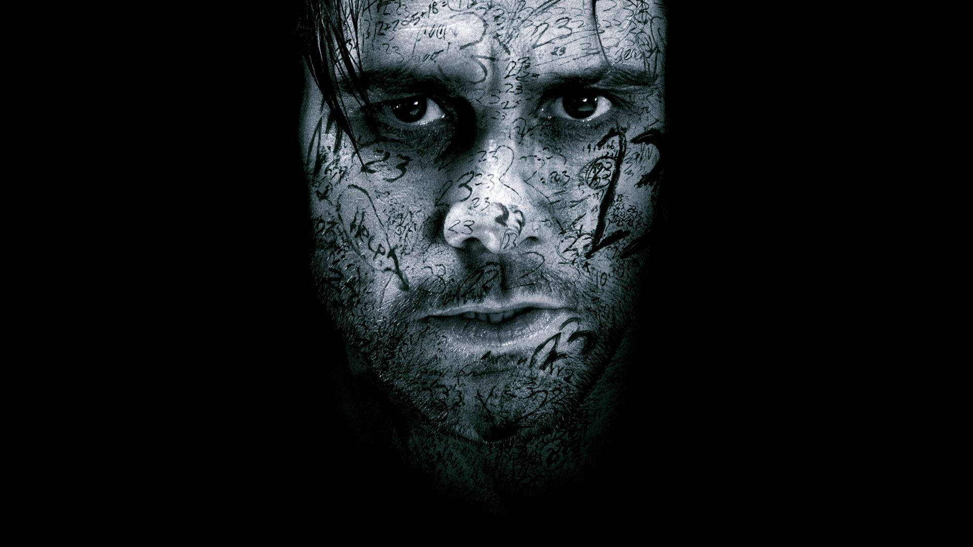 Jim Carrey 桌布 壁紙 — 一個令人毛骨悚然的特寫，男人的臉上佈滿了塗鴉文字，背景為黑色。