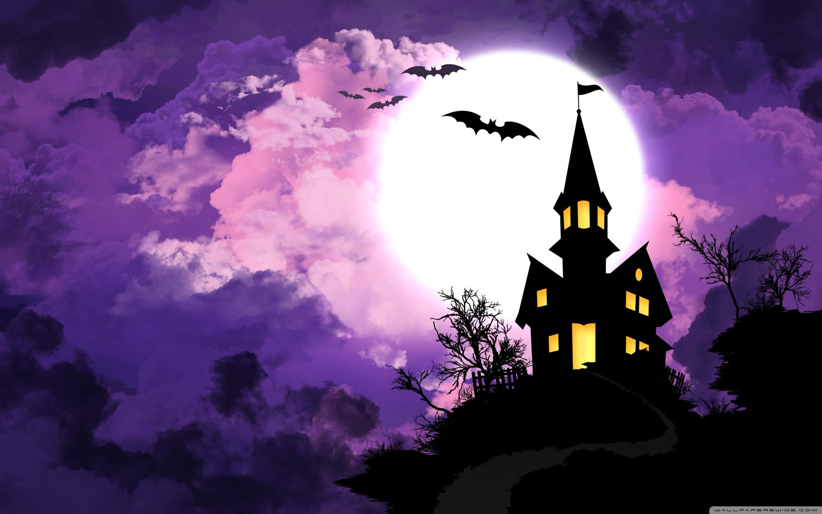Spooky Halloween 桌布 壁紙 — 一個令人毛骨悚然的鬼屋剪影，窗戶發著光，矗立在滿月下，蝙蝠在紫色多雲的天空中飛翔。