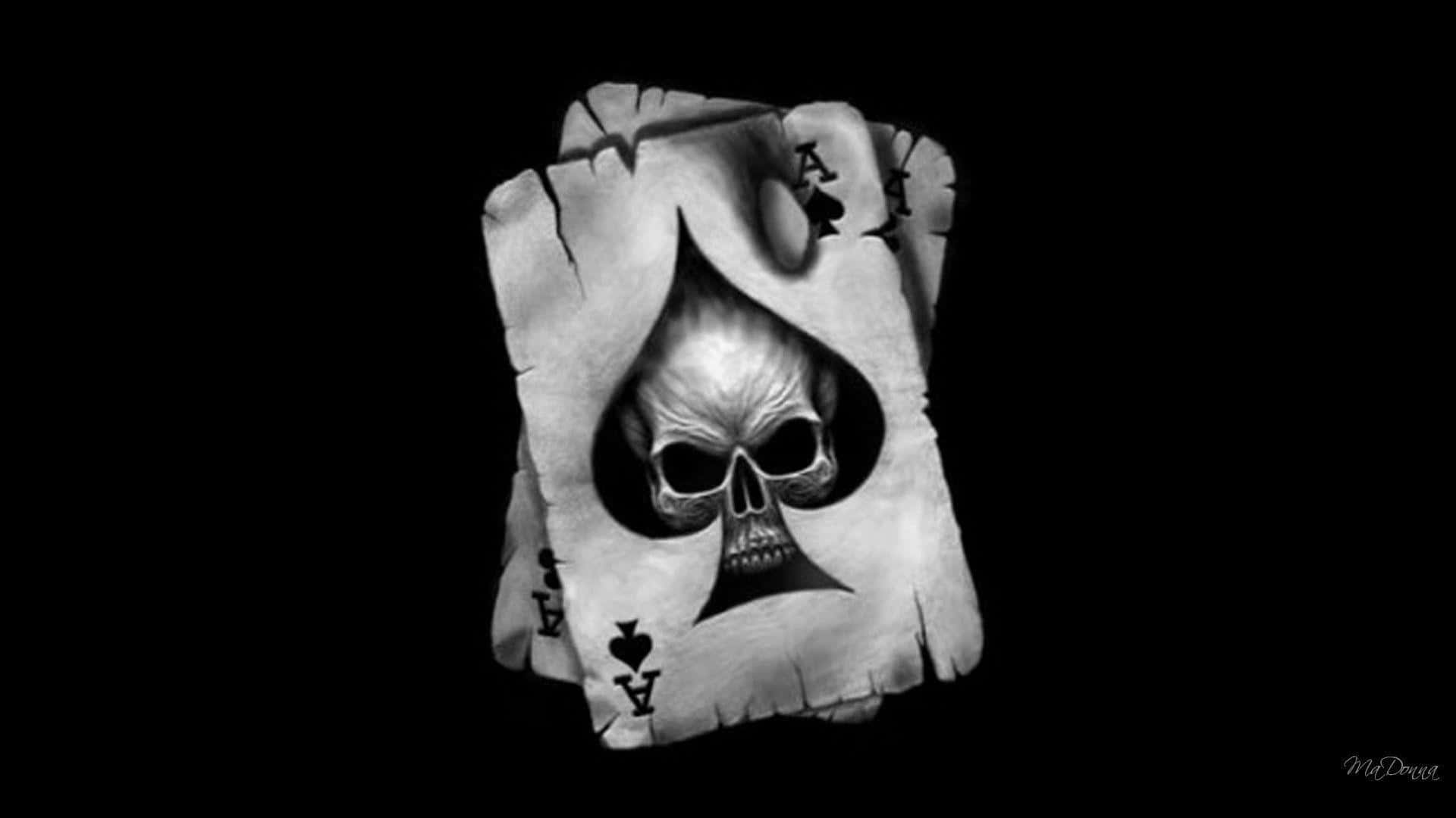 Black Skeleton 桌布 壁紙 — 一個令人毛骨悚然的黑白骷髏頭從一張破爛的黑桃A撲克牌中浮現，背景為黑色虛空。
