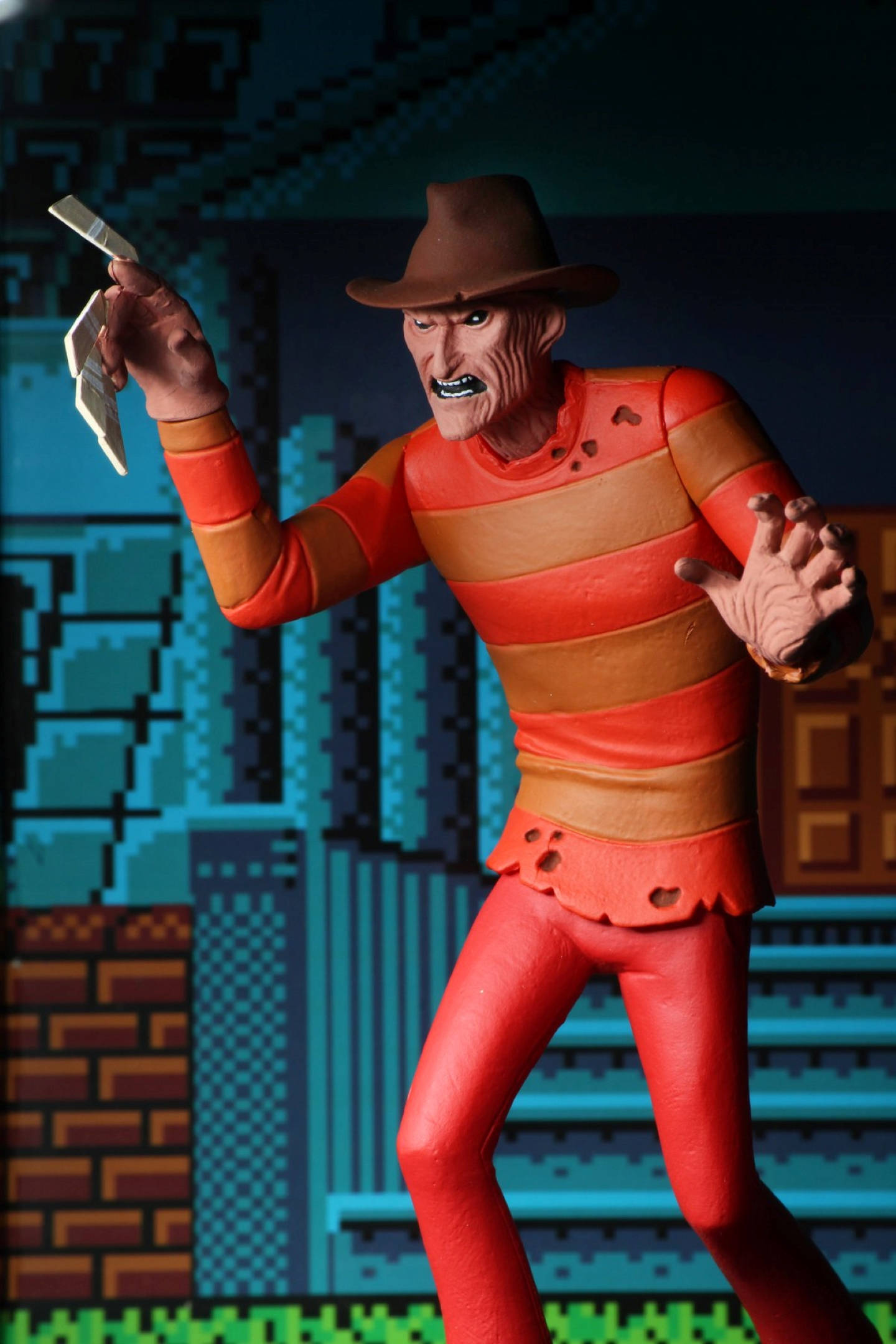Freddy 桌布 壁紙 — 一個令人畏懼的佛萊迪·克魯格人偶，身穿其標誌性條紋毛衣，在像素化電玩背景前手持刀刃。