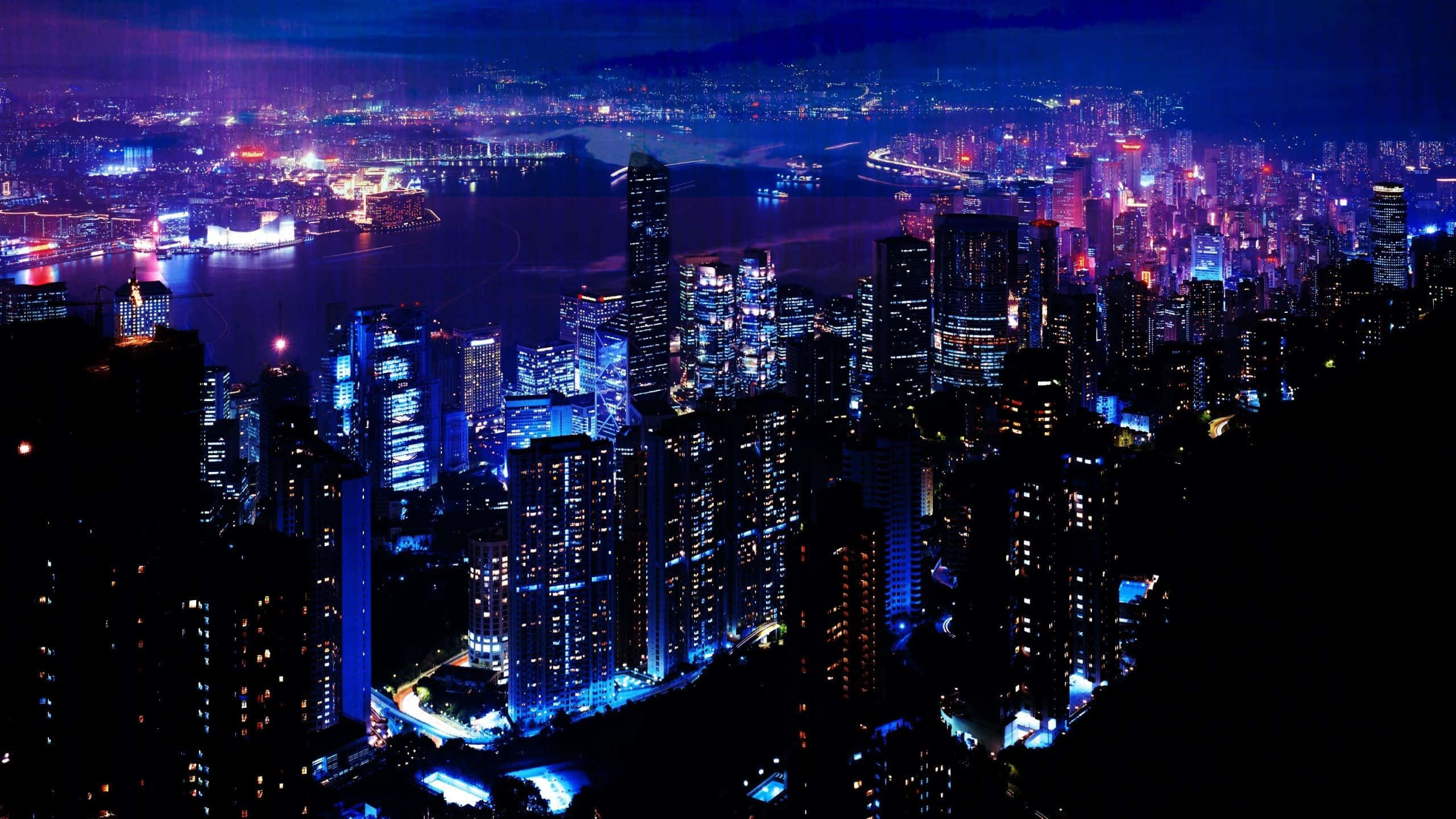 Cyberpunk Night City 桌布 壁紙 — 一個令人眼花繚亂的夜景城市景觀，高聳的摩天大樓在港口上空閃爍著藍色和紫色的燈光。