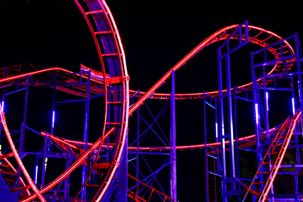 Roller Coaster 桌布 壁紙 — 一個令人興奮的雲霄飛車，在漆黑的夜空中被鮮豔的紅色和藍色霓虹燈照亮。
