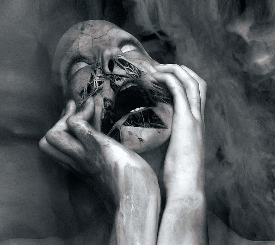 Freaky 桌布 壁紙 — 一個令人難忘的黑白肖像，描繪一張腐爛的人臉，根從嘴巴和眼睛長出，被雙手捧著，背景煙霧瀰漫。