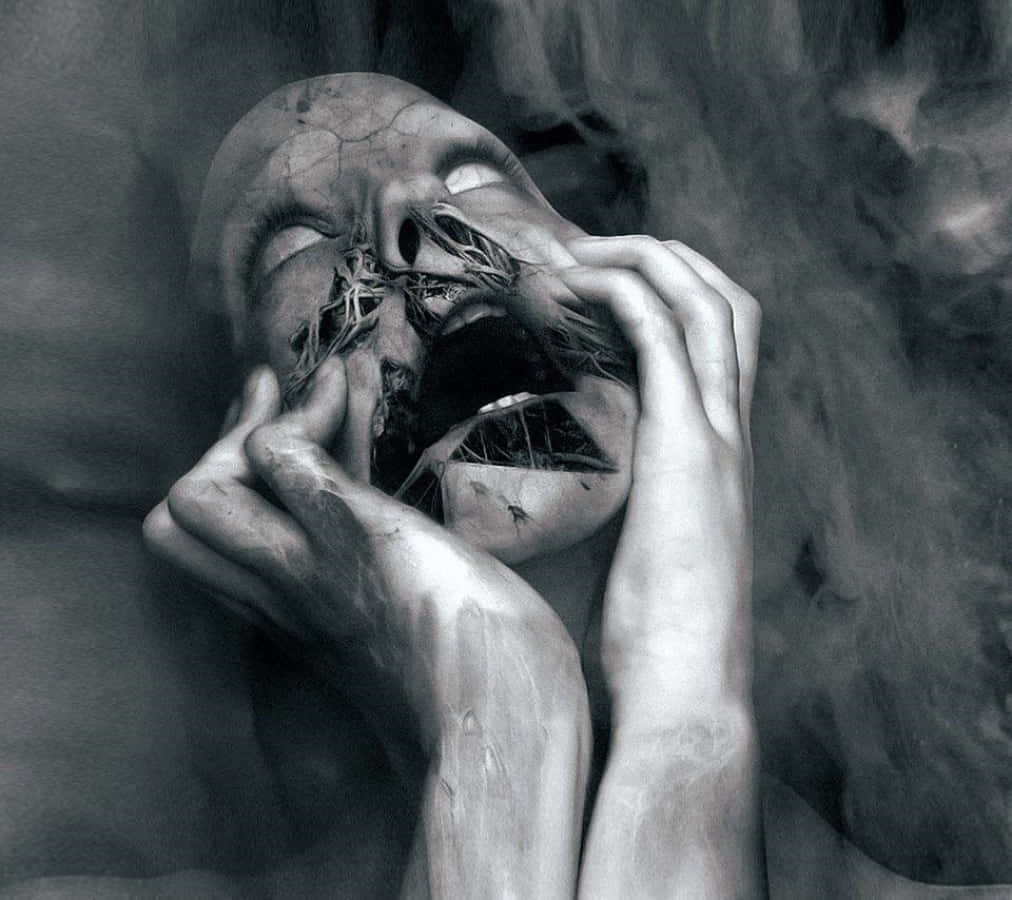 Scary Face 桌布 壁紙 — 一個令人難忘的黑白肖像，描繪一張腐爛的人臉，雙手緊抓著它破碎的面容，背景煙霧繚繞。