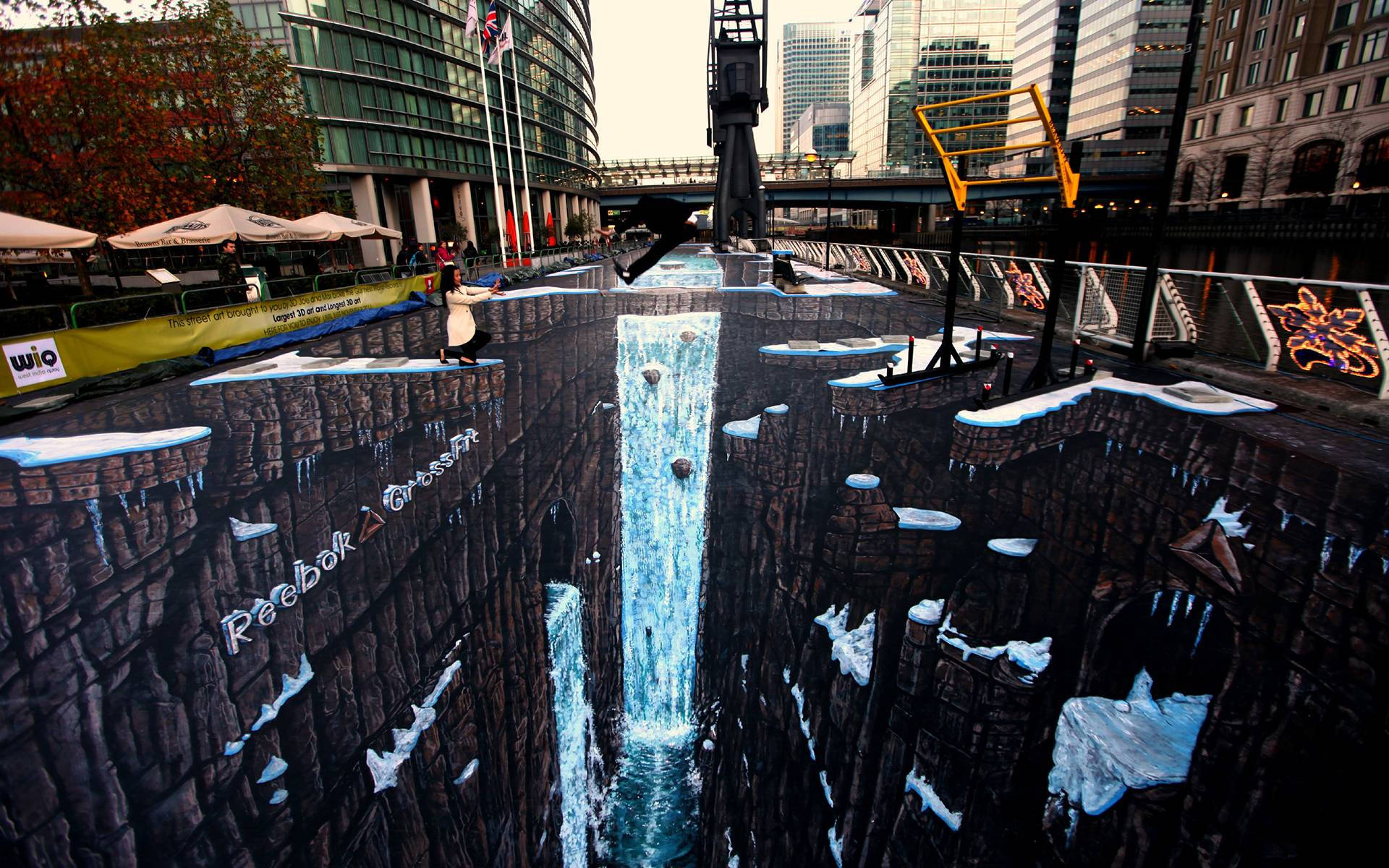 Urban 桌布 壁紙 — 一個令人驚嘆的3D粉筆藝術幻覺，描繪了一個雪峽谷、瀑布和冰崖，畫在城市街道上。