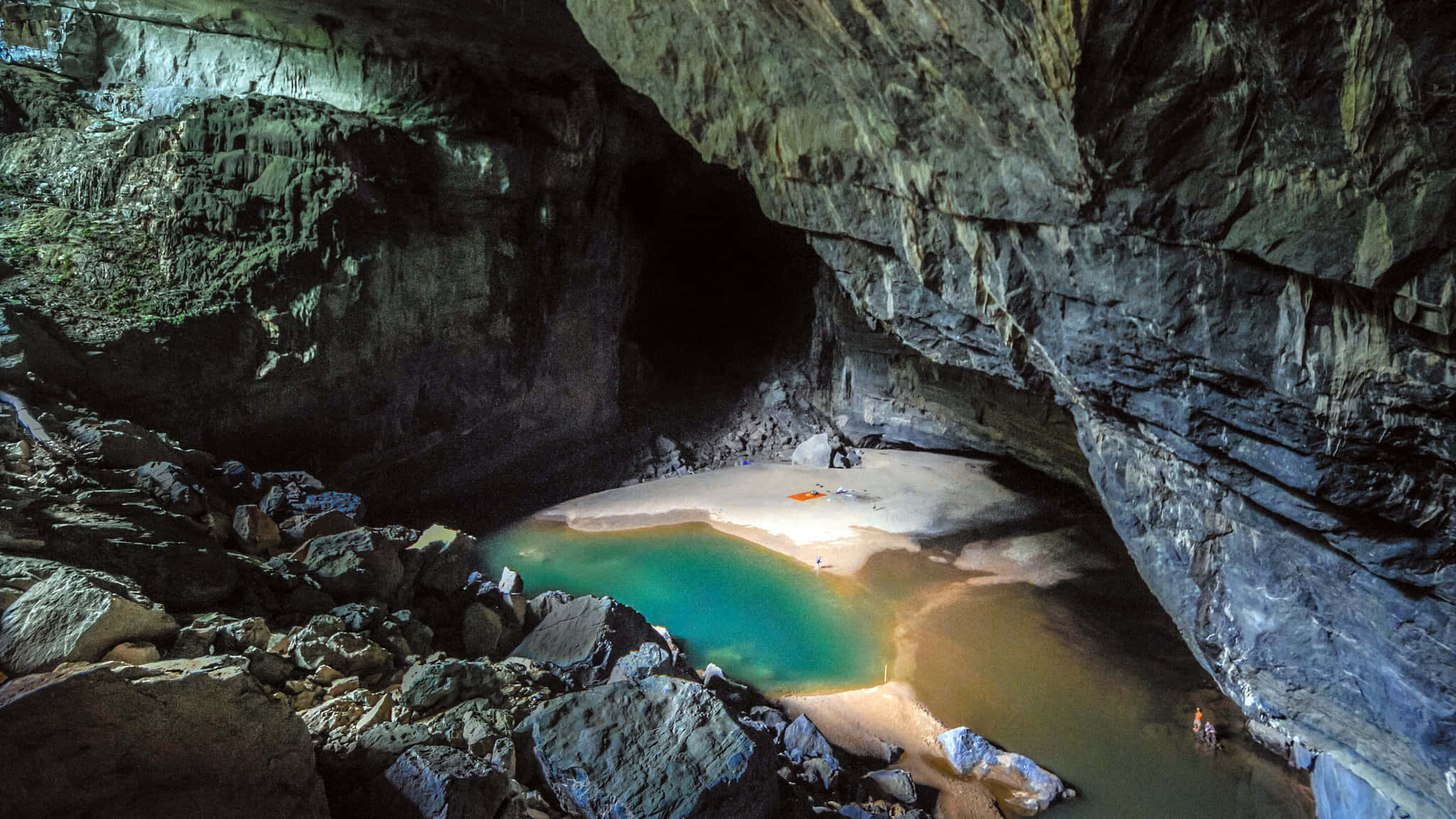 Cave 桌布 壁紙 — 一個令人驚嘆的地下洞穴池，擁有碧綠色的水和沙灘，周圍環繞著崎嶇的岩層。
