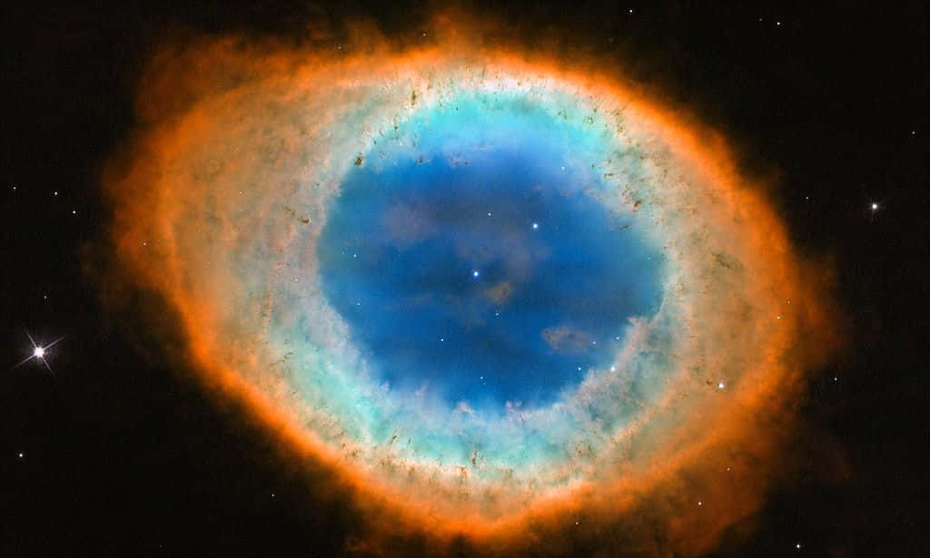 Interstellar Cloud 桌布 壁紙 — 一個令人驚嘆的宇宙眼睛星雲，在繁星點點的黑色虛空中散發著充滿活力的藍色中心和火熱的橙色邊緣。