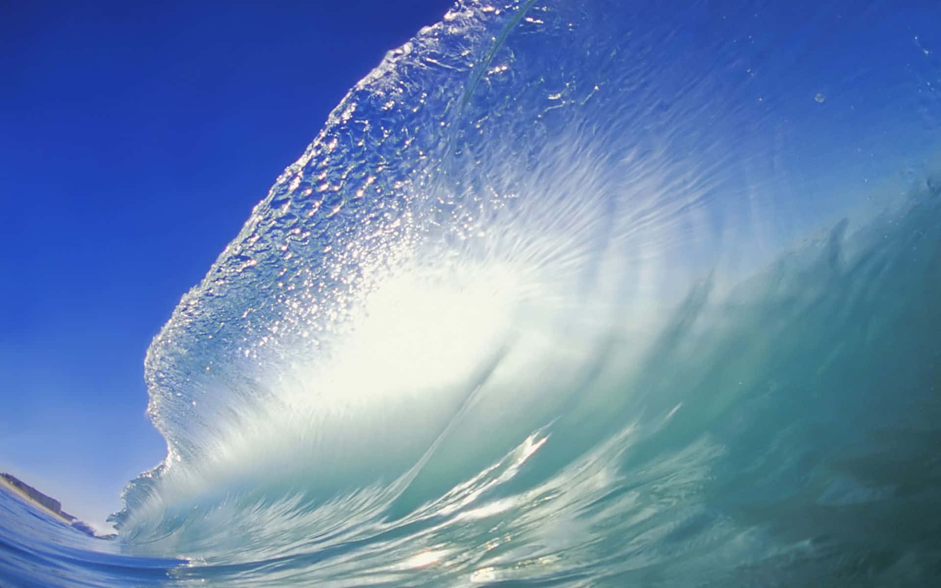 Ocean Waves 桌布 壁紙 — 一個令人驚嘆的水下視角，展現一道捲曲的海浪，陽光穿透其半透明的藍綠色形態。