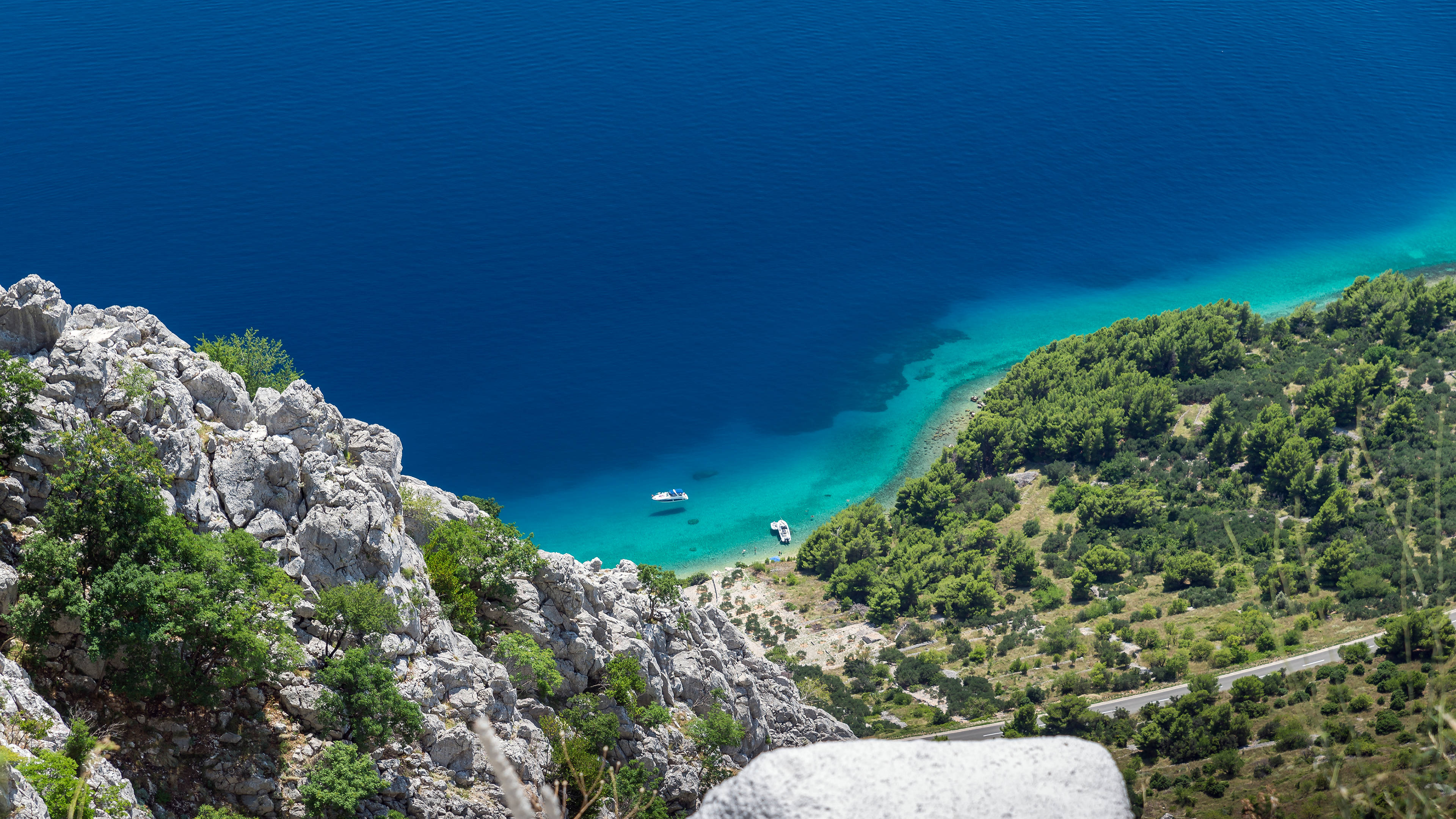 Croatia 桌布 壁紙 — 一個令人驚嘆的海岸小海灣，碧綠的海水隱藏在崎嶇的懸崖和茂密的綠植之間，沐浴在明亮的陽光下。
