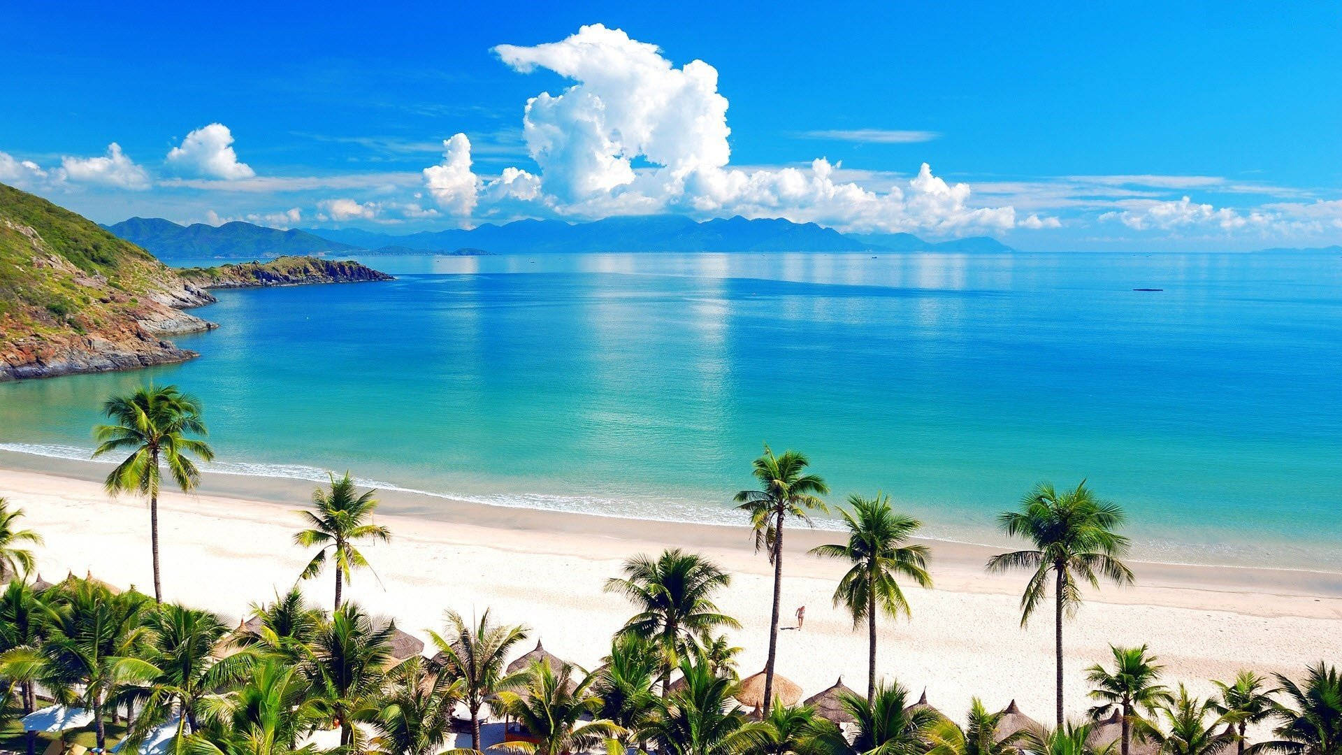 Jamaica 桌布 壁紙 — 一個令人驚嘆的熱帶海灘，擁有碧綠的海水、白色的沙灘和棕櫚樹，在明亮的藍天下有蓬鬆的雲朵。