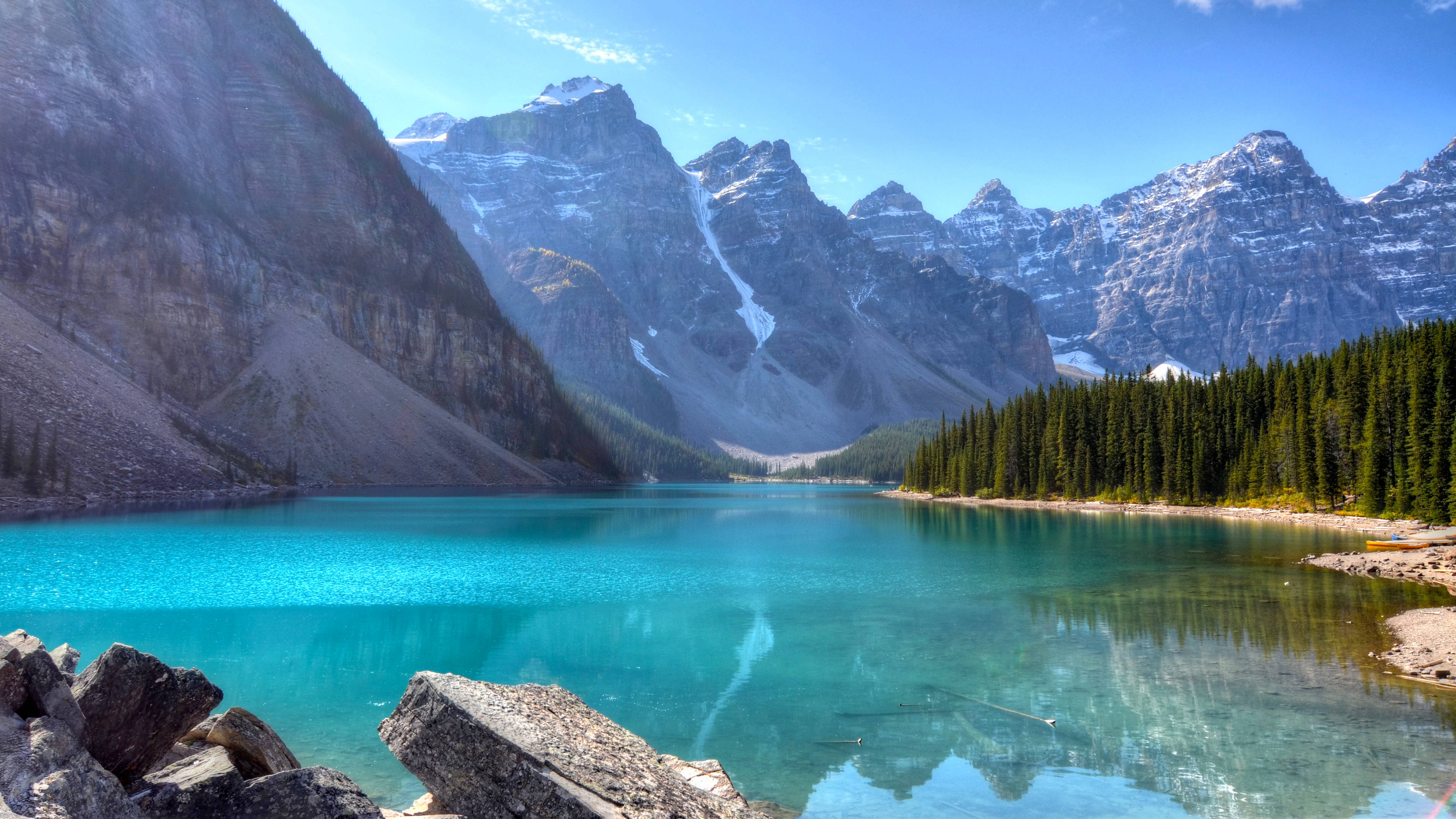 Lake 桌布 壁紙 — 一個令人驚嘆的碧綠湖泊，在清澈的藍天下映照著白雪覆蓋的山脈和常綠森林。