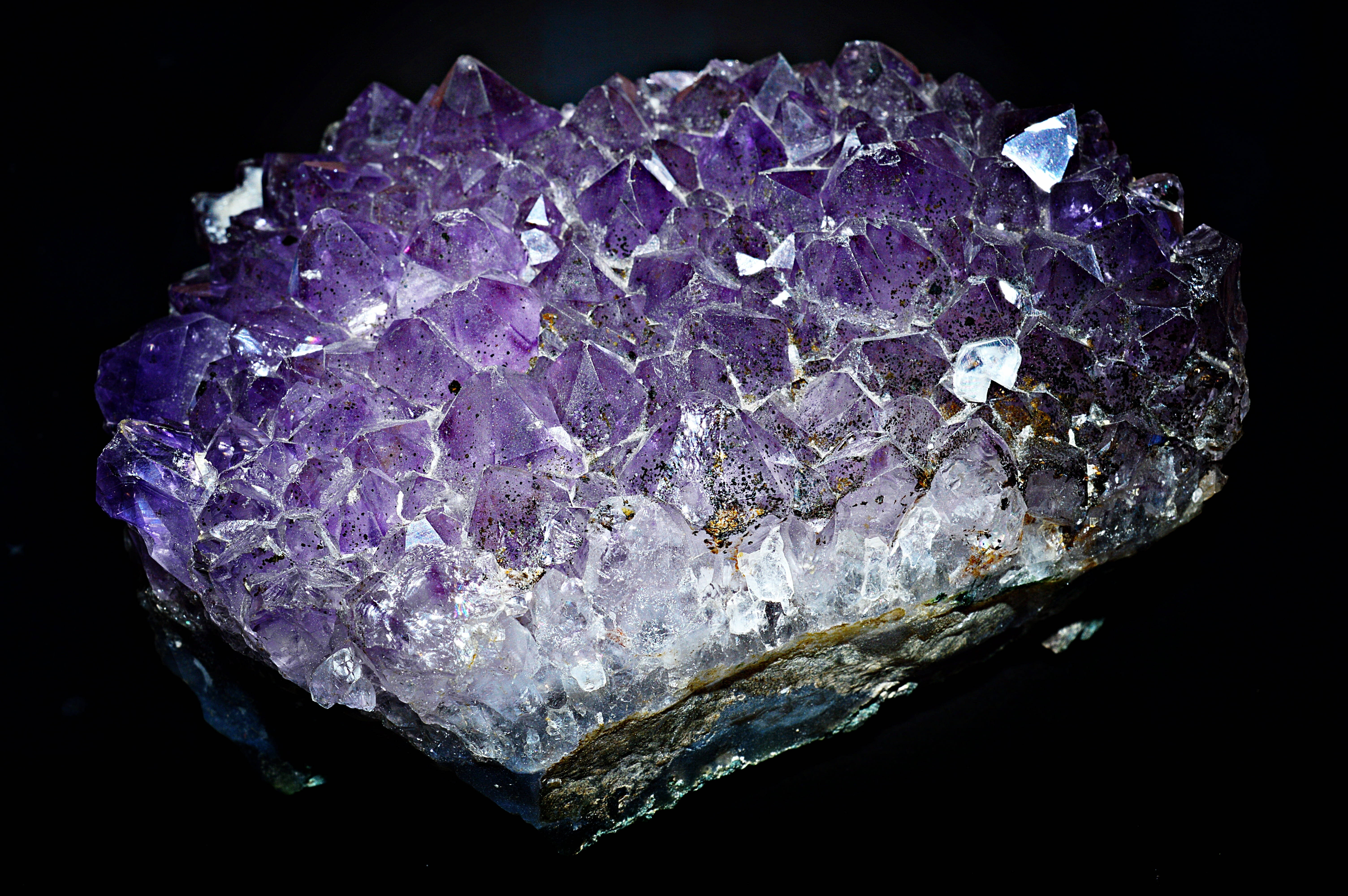紫水晶 桌布 壁紙 — 一個令人驚嘆的紫水晶晶體簇在純黑背景下散發出深紫色調的光芒。