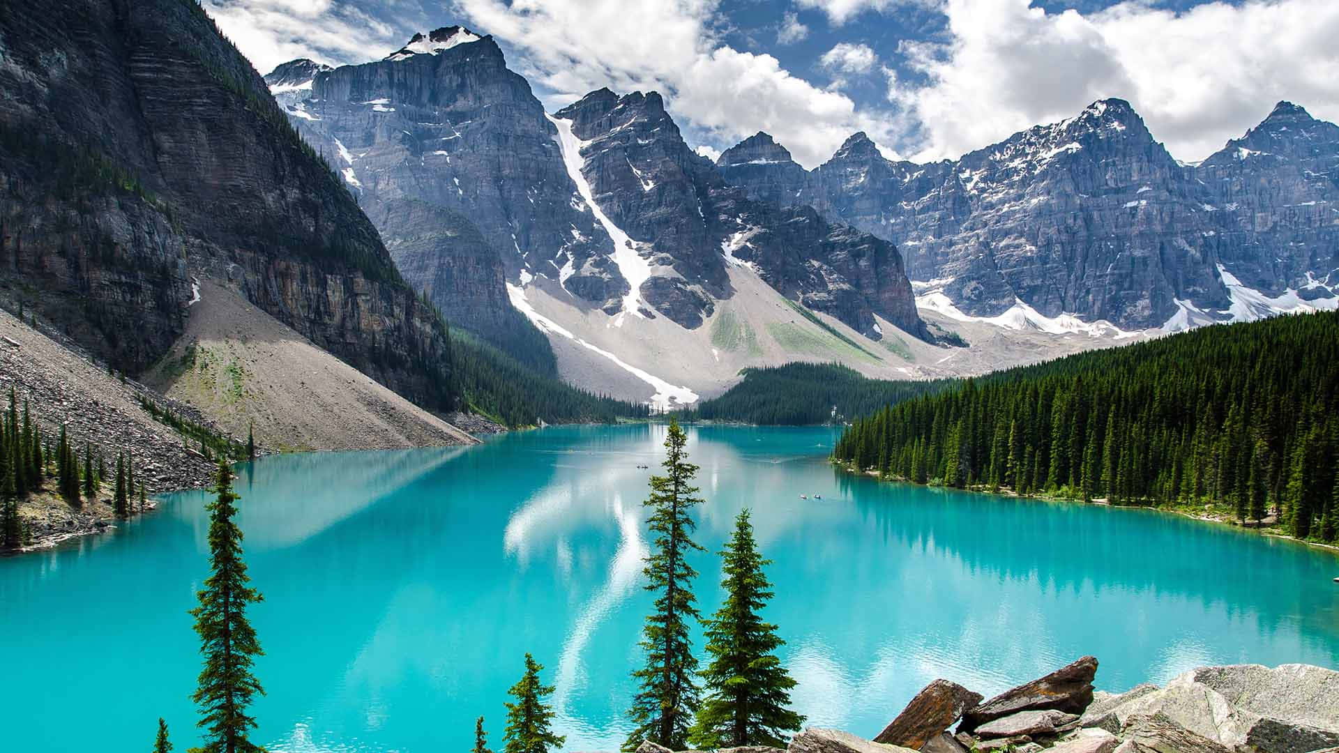 Beautiful Place 桌布 壁紙 — 一個令人驚嘆的綠松石湖，在明亮的藍天下映照著白雪覆蓋的山脈和蓬鬆的雲朵。