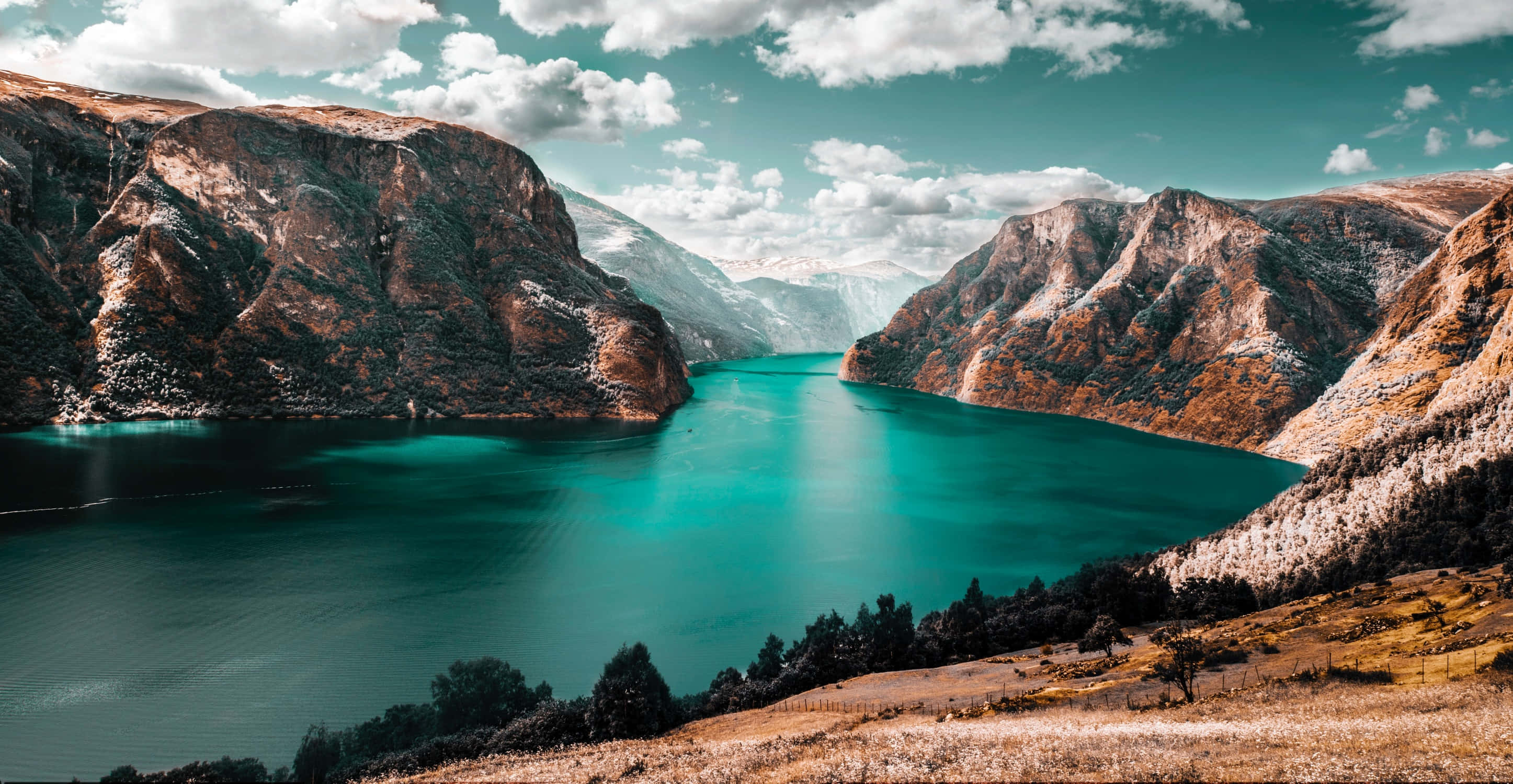 Beautiful Landscape 桌布 壁紙 — 一個令人驚嘆的藍綠色湖泊，坐落在崎嶇的棕色山脈之間，天空部分多雲。