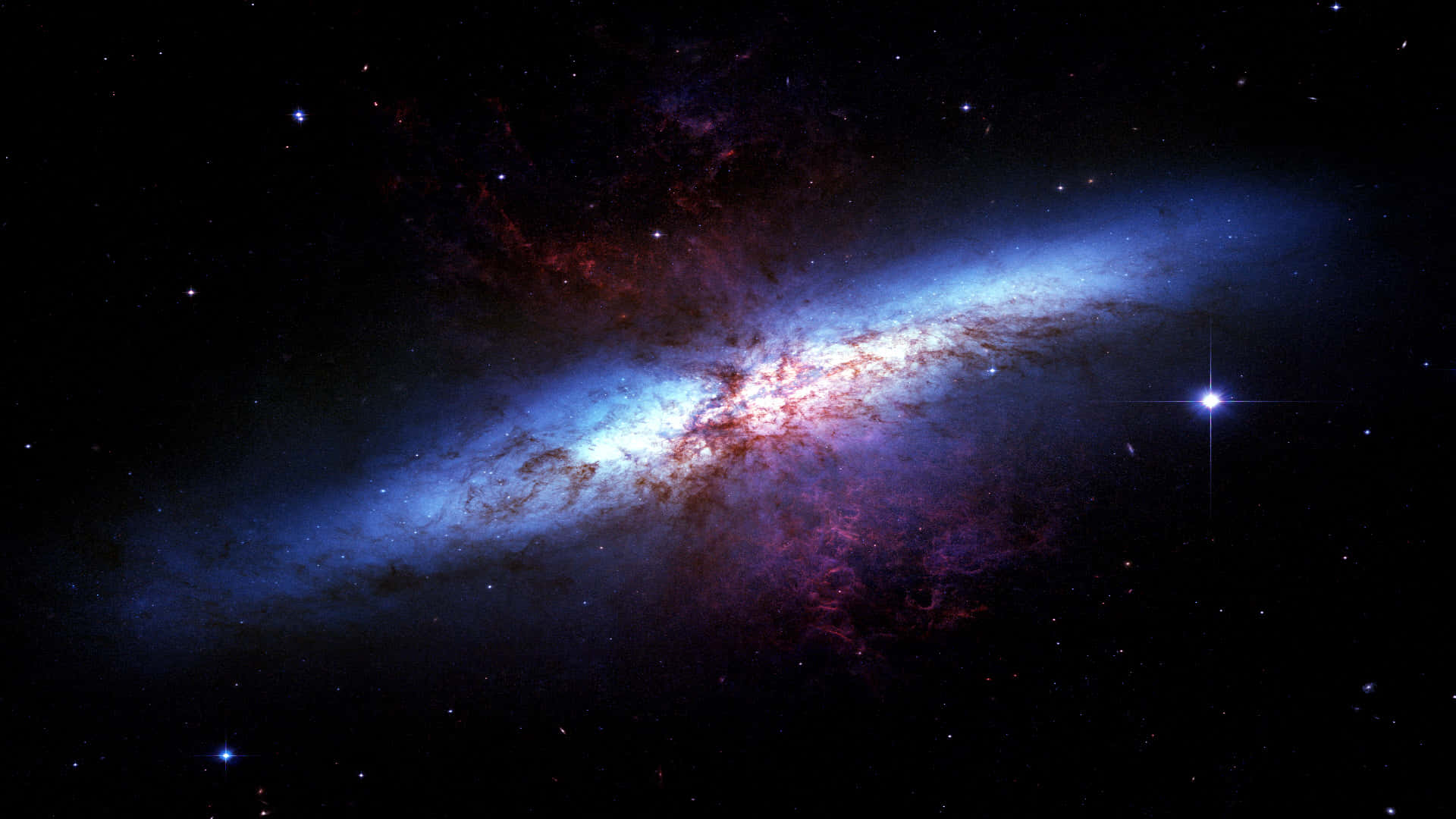 銀河 桌布 壁紙 — 一個令人驚嘆的螺旋星系，在佈滿星辰的宇宙虛空中閃耀著藍色和紅色的星雲。