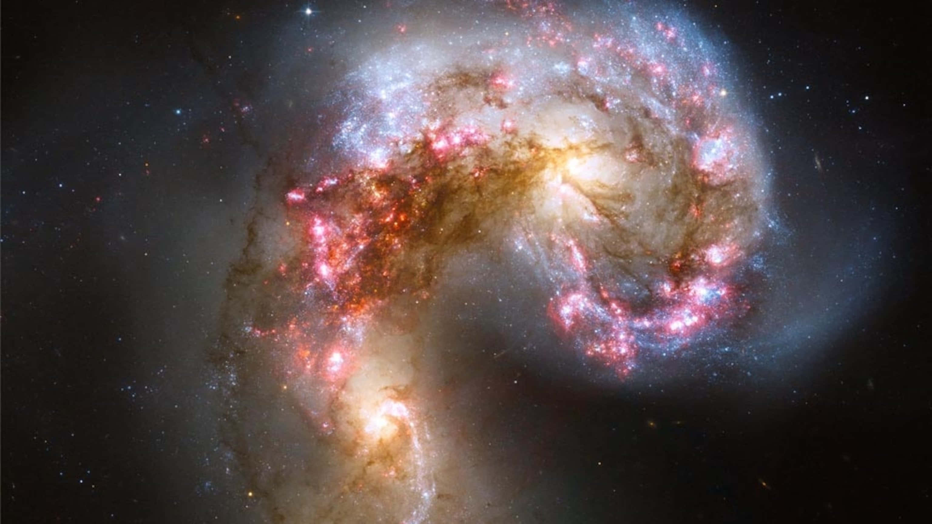 Elliptical Galaxy 桌布 壁紙 — 一個令人驚嘆的螺旋星系，帶有發光的粉紅色和橙色恆星形成區域，在黑暗的宇宙背景下旋轉。