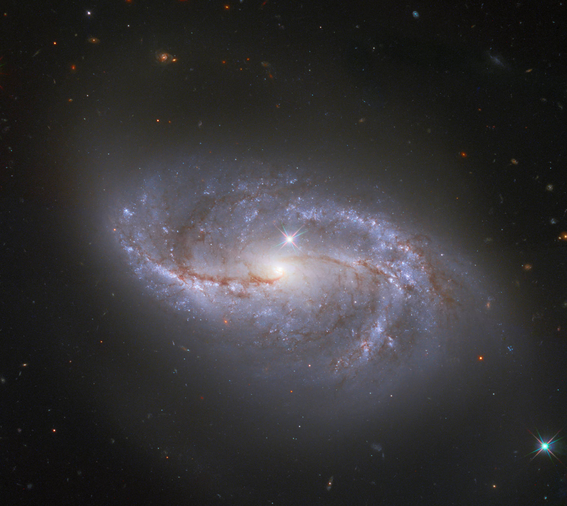 一個螺旋星系，在星場中有藍色旋臂和橙色塵埃帶。 — 星雲 GIF 壁紙