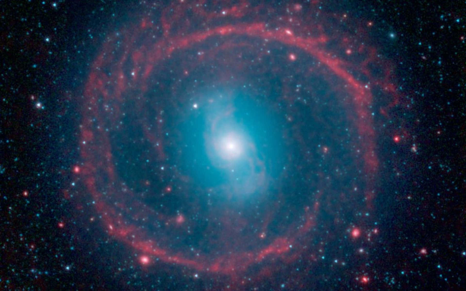 Real Space 桌布 壁紙 — 一個令人驚嘆的螺旋星系，帶有發光的紅色旋臂和明亮的藍色核心，周圍環繞著無數恆星。