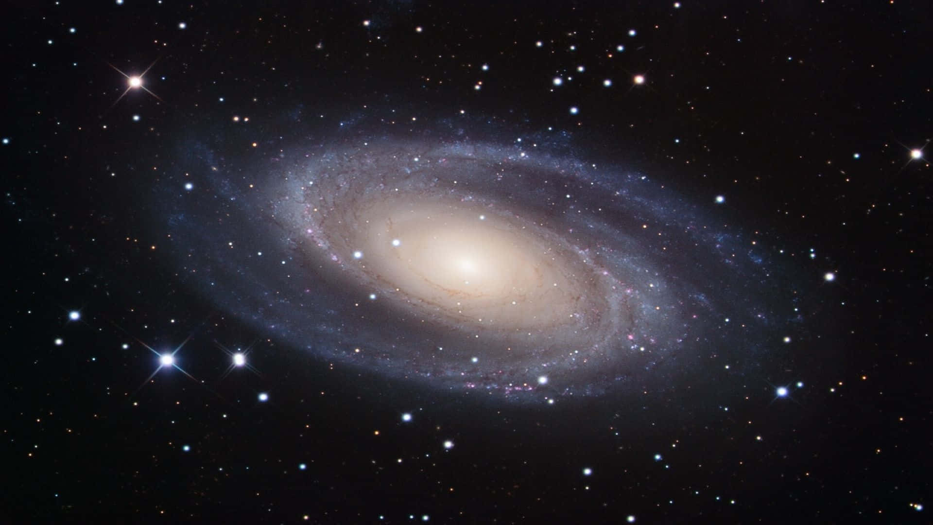 酷炫太空 桌布 壁紙 — 一個令人驚嘆的螺旋星系，擁有發光的旋臂和明亮的星星，背景是深邃的黑色宇宙。