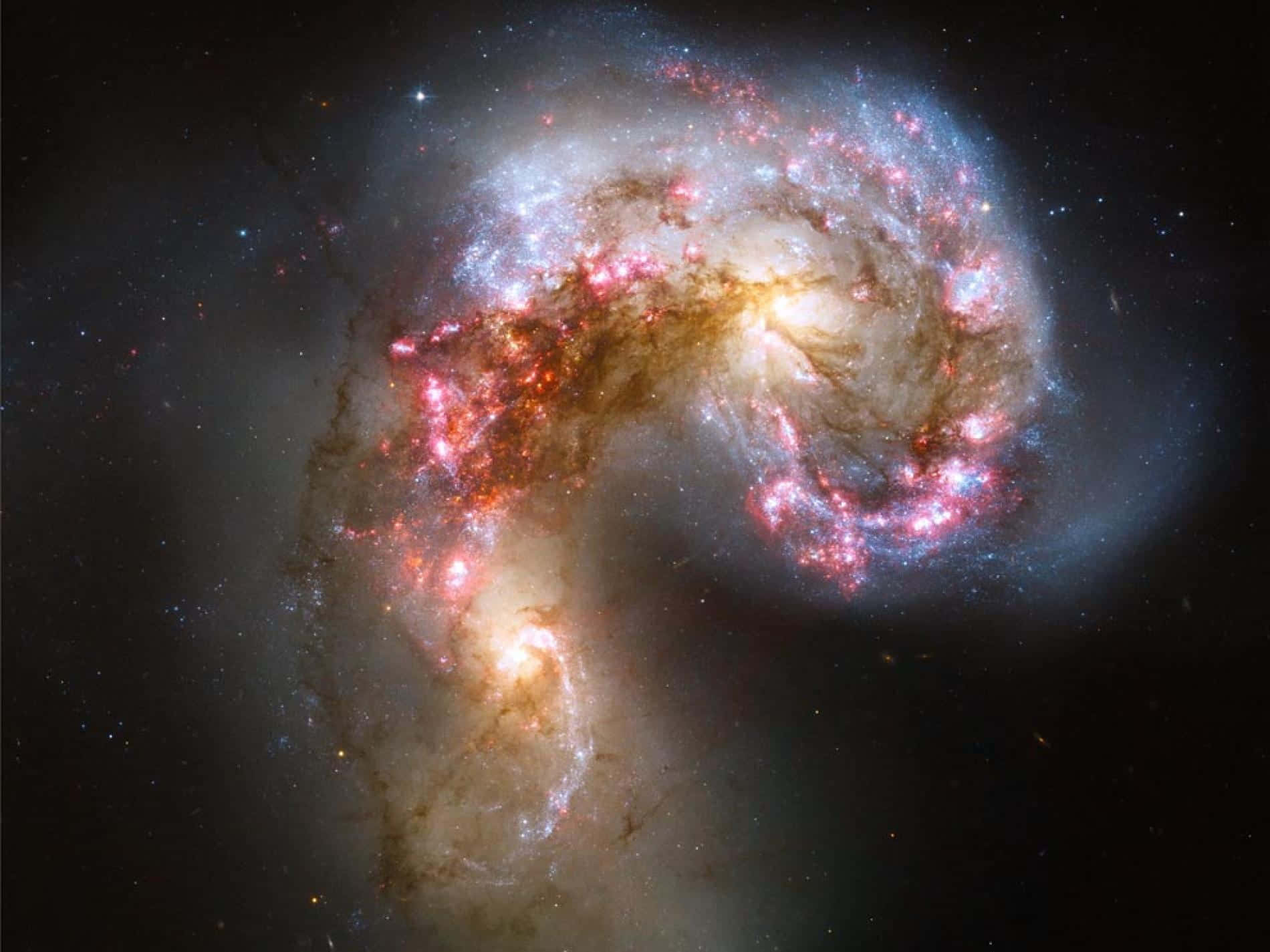 Real Galaxy 桌布 壁紙 — 一個令人驚嘆的螺旋星系，發光的粉紅色和藍色星團在黑暗的宇宙背景下碰撞。