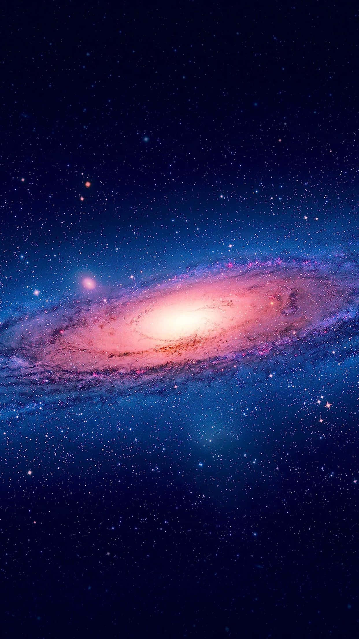 太空 桌布 壁紙 — 一個令人驚嘆的螺旋星系在繁星點點的宇宙背景下發出粉紅色和藍色的光芒。