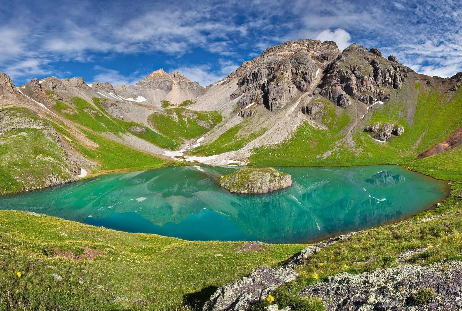 Colorado Mountains 桌布 壁紙 — 一個令人驚嘆的高山湖泊，碧綠色的湖水映照著崎嶇的山脈，在明亮的藍天和散落的雲朵下。