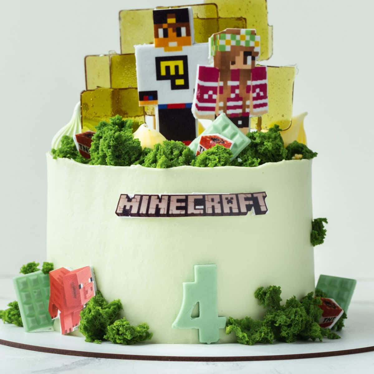 Minecraft Cakes 桌布 壁紙 — 一個以Minecraft為主題的生日蛋糕，上面有像素化的角色和方塊，並覆蓋著綠色糖霜。